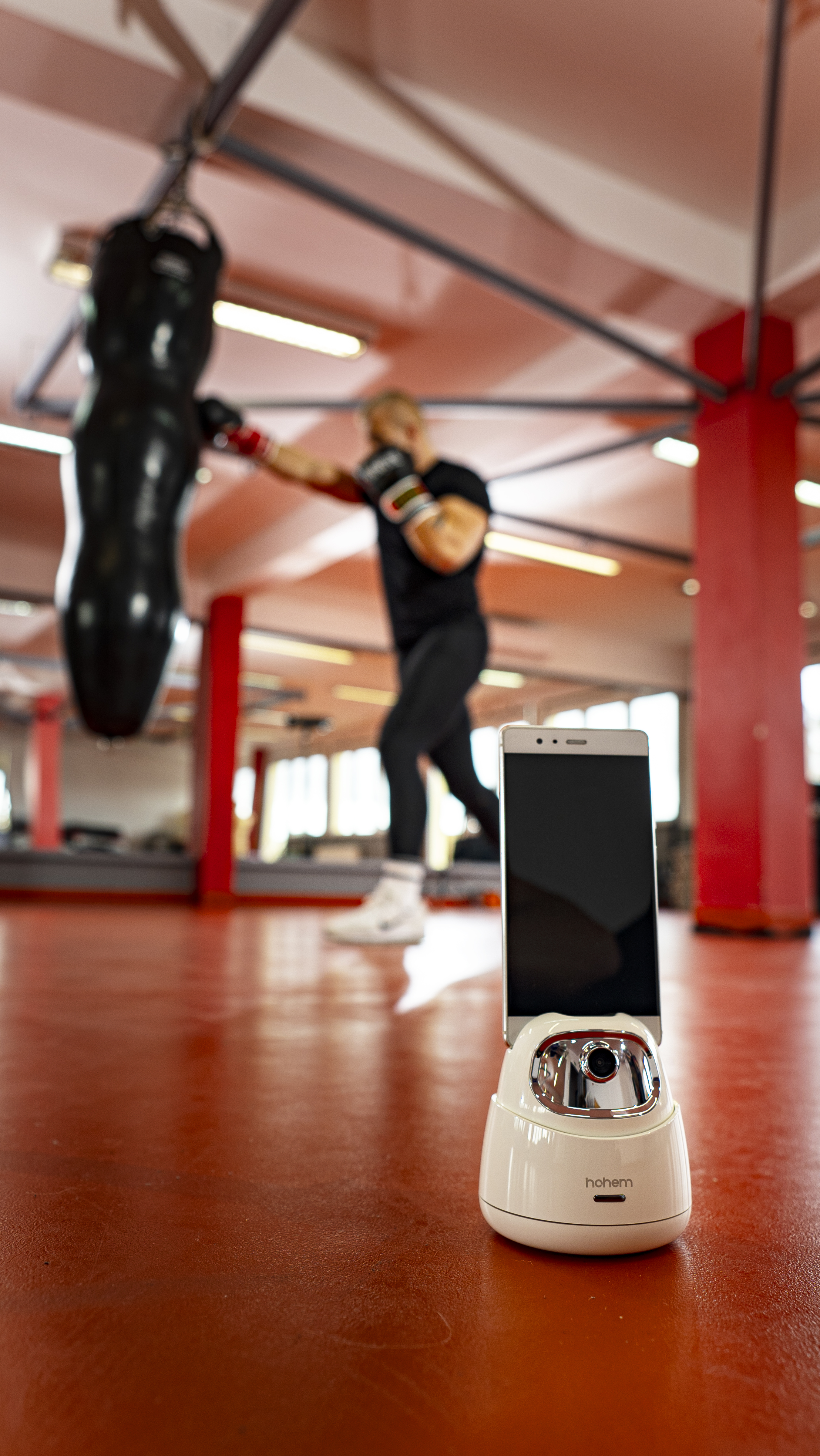 Eine Person boxt mit einem Boxsack. Ein Telefon mit Ständer liegt auf dem Boden.