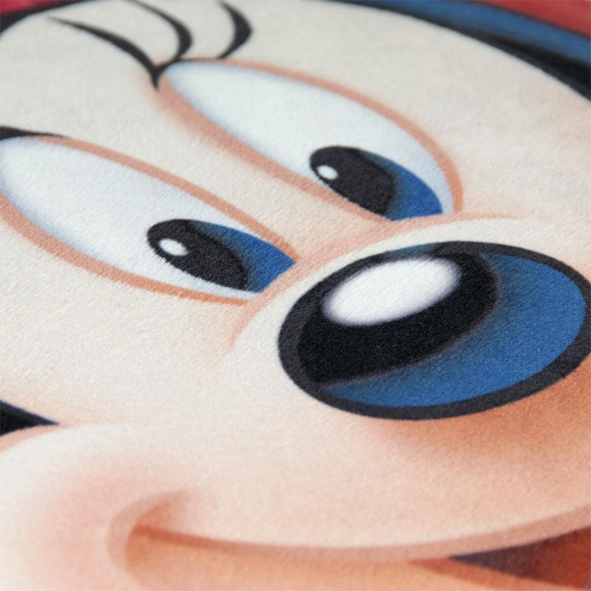 Primer plano de la cara de Mickey Mouse. Ojos grandes, pupilas negras y reflejos azules. Piel rosada, nariz negra grande. Fondo rojo.