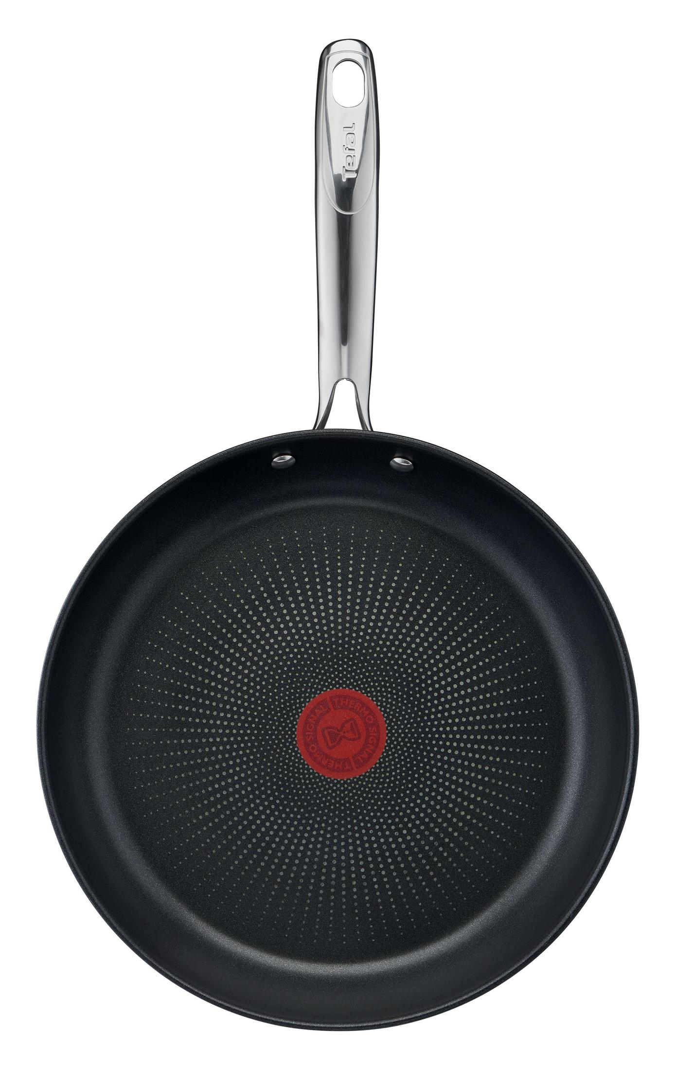 A black frying pan with a silver handle, a red center, and a dotted pattern on its cooking surface.