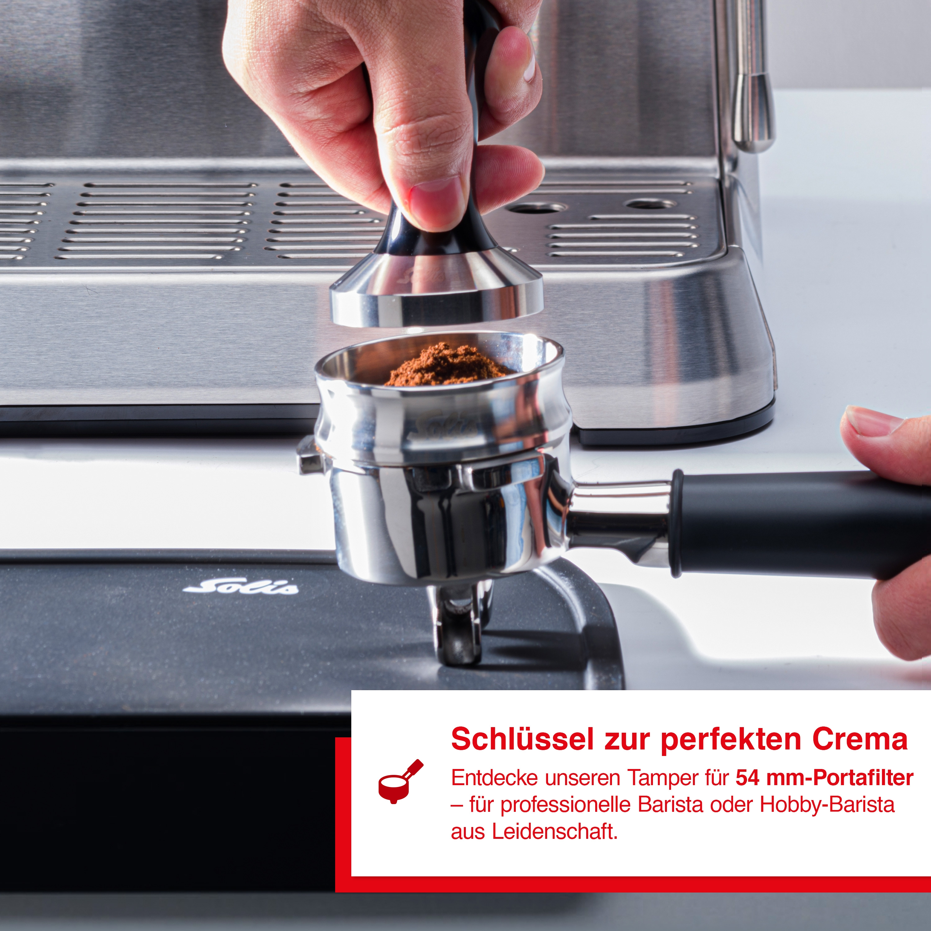 Hand hält Tamper und drückt Kaffeemehl in einen Siebträger einer Espressomaschine.