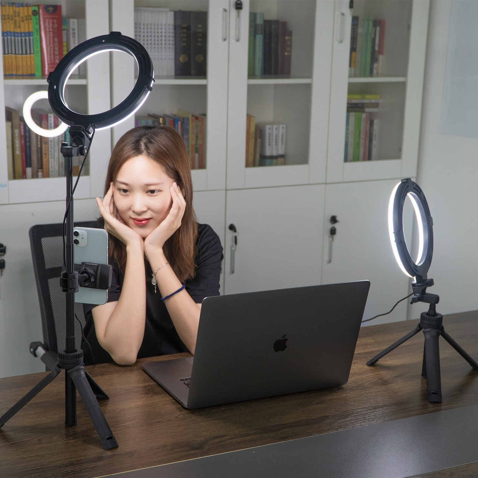 Een vrouw met een laptop gebruikt ringlichten voor video. Twee ringlichten en een telefoonhouder.