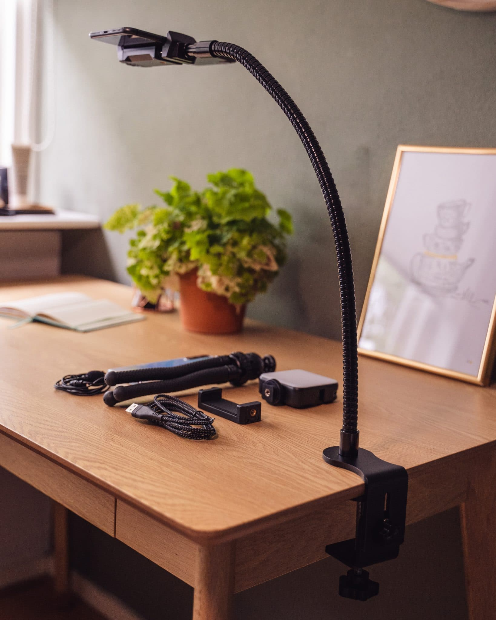 Een bureauopstelling met een flexibele armlamp, een telefoonhouder, een statief en andere accessoires.
