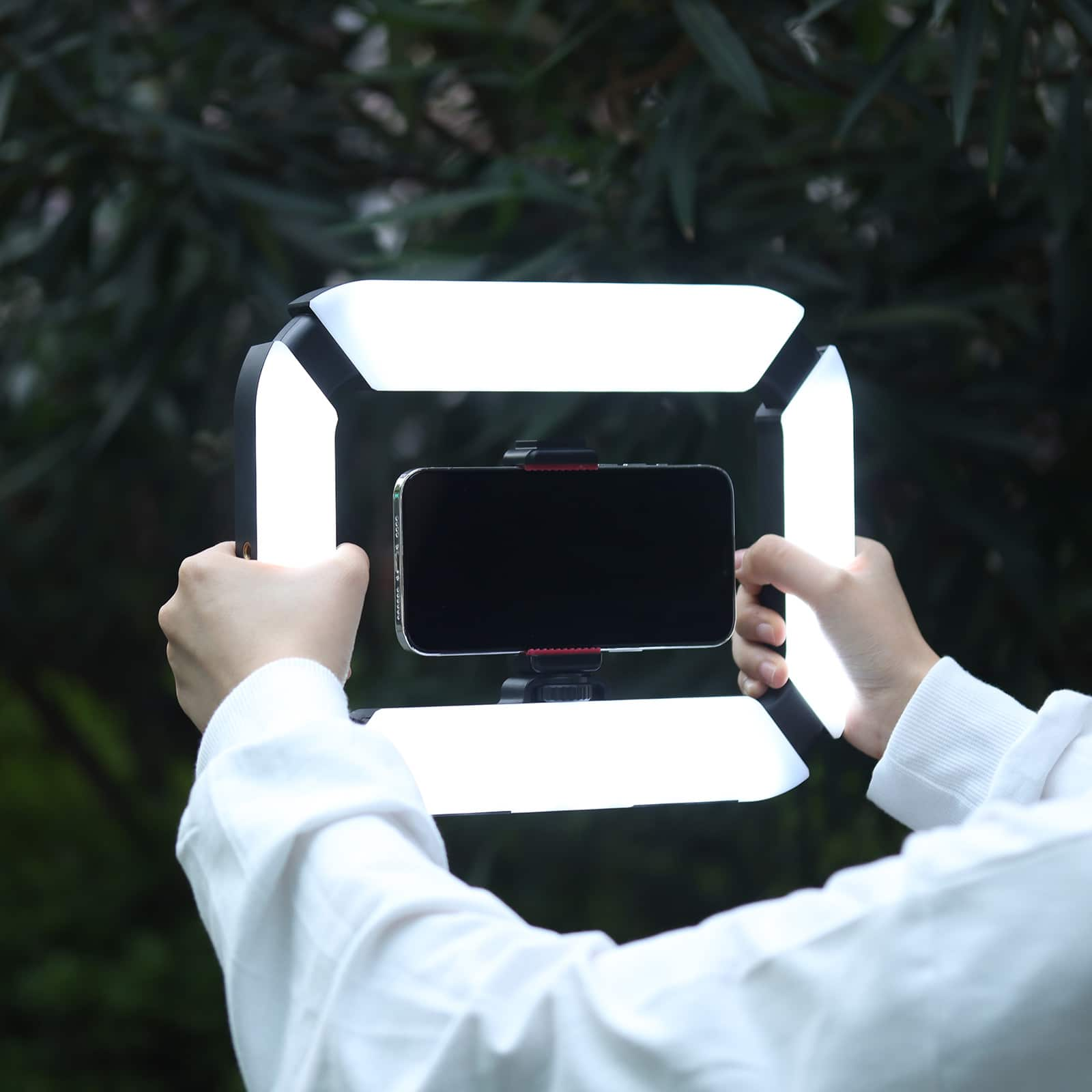 Persona che tiene una luce per un telefono. La luce è bianca e nera.