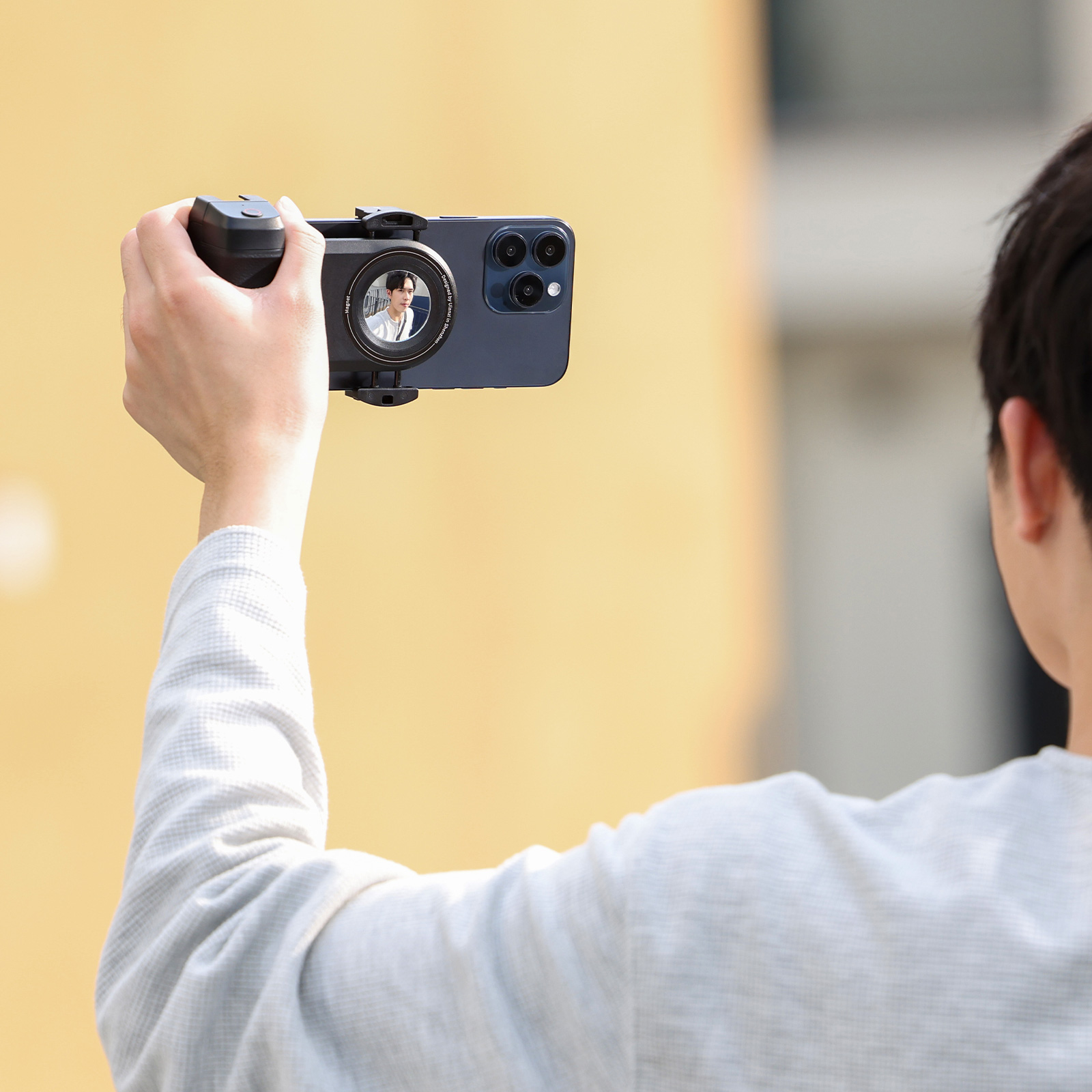 Osoba trzymająca smartfona z nakładką na aparat, robiąca zdjęcie.