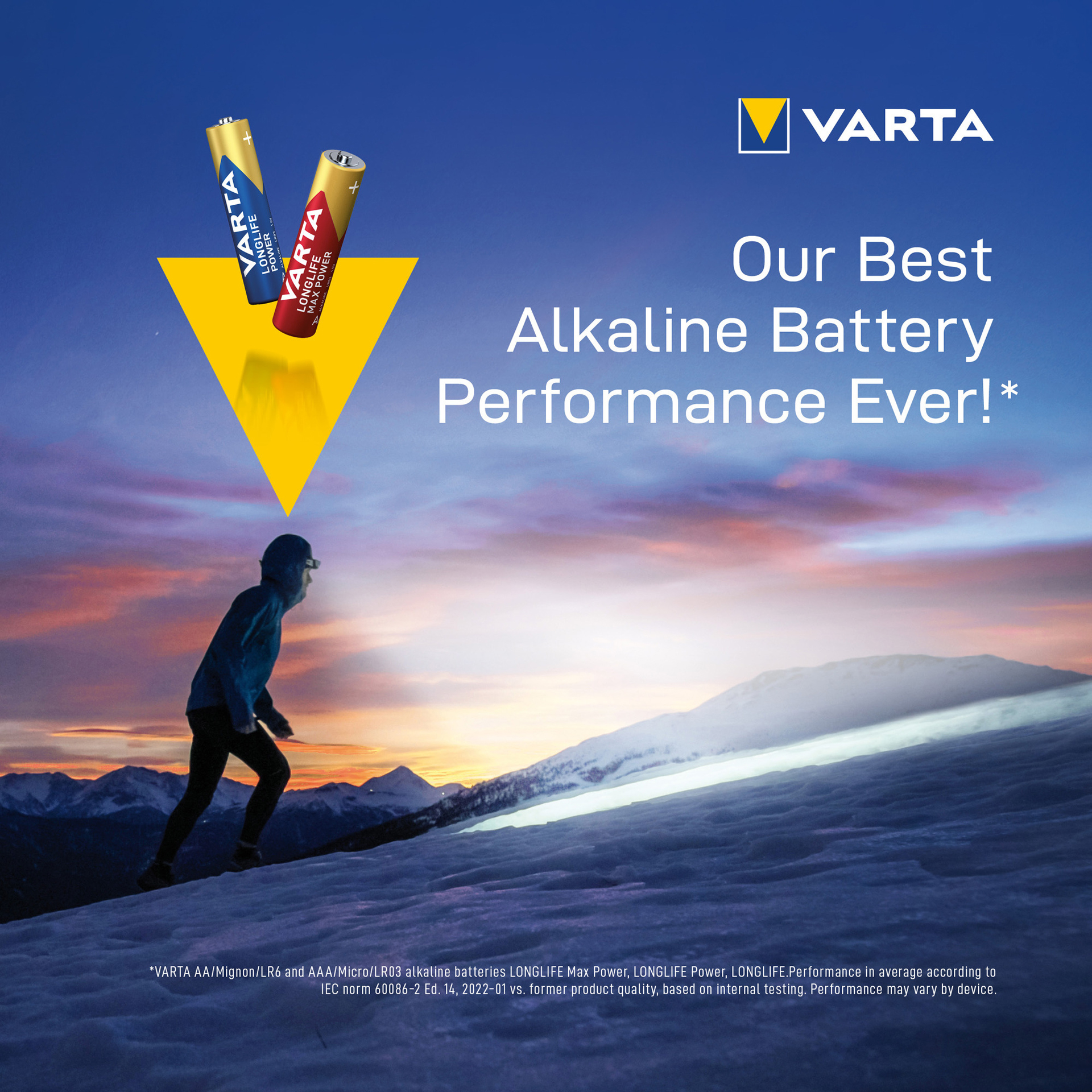 Two batteries are placed on a mountain with a person walking. A yellow triangle is in the foreground.