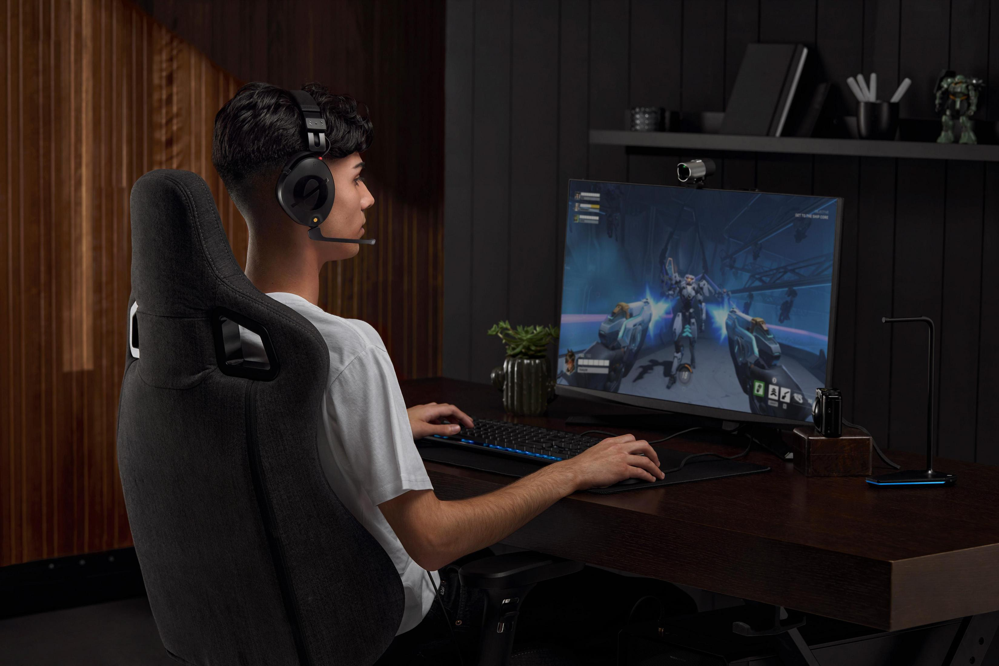 Mężczyzna w zestawie słuchawkowym gra w gry wideo na komputerze. Ciemne otoczenie pokoju.
