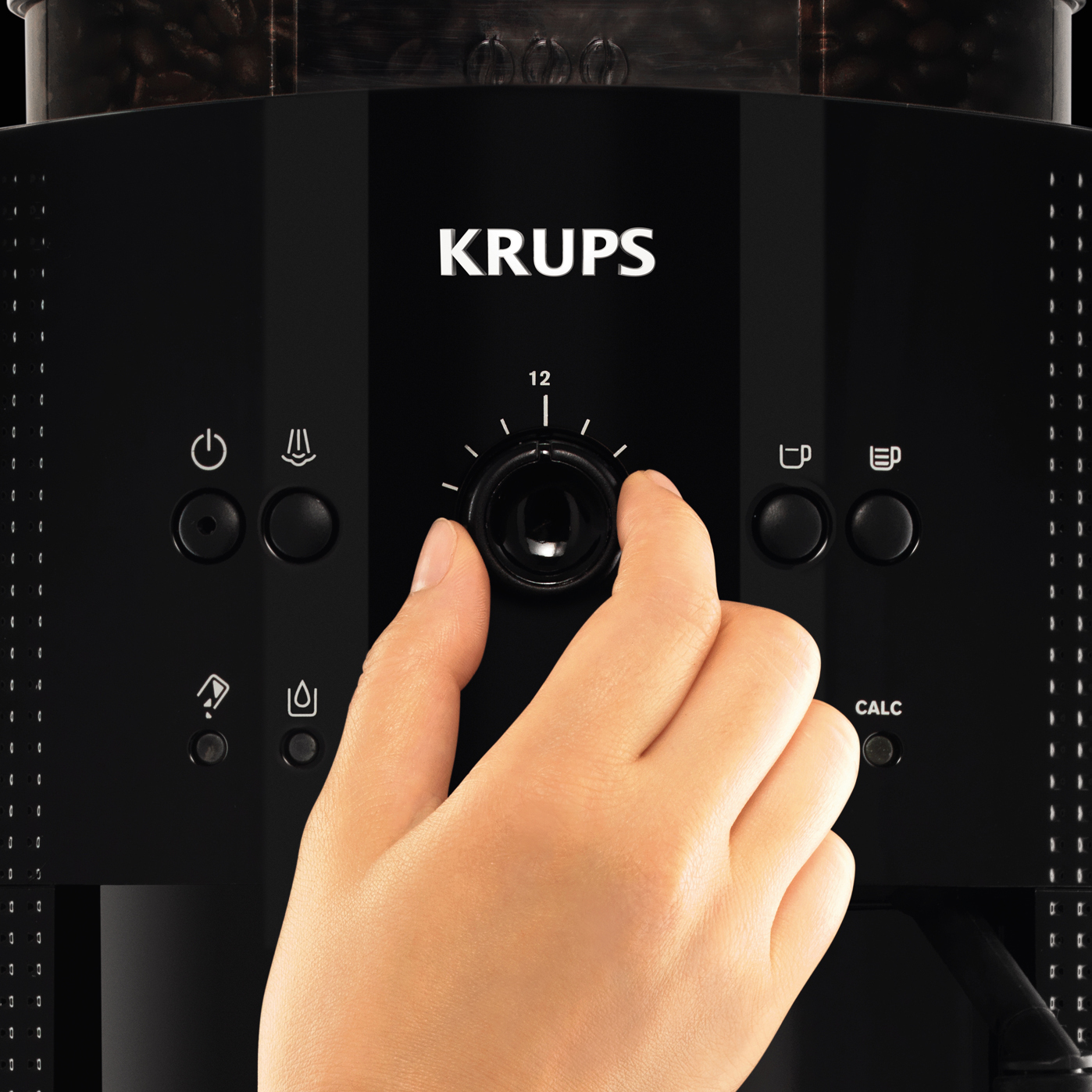 Hand, die den Drehregler an einer schwarzen Krups-Kaffeemaschine einstellt, mit verschiedenen Funktionstasten.