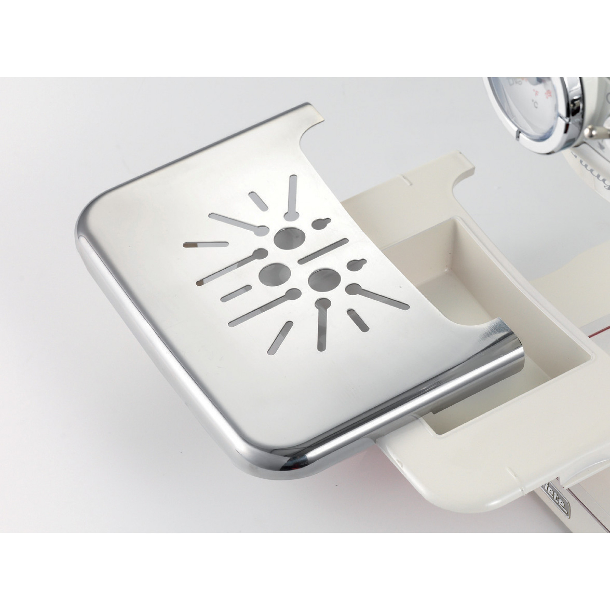 Nahaufnahme eines Metalltabletts einer Kaffeemaschine. Es hat Schlitze und ein herausnehmbares Fach.