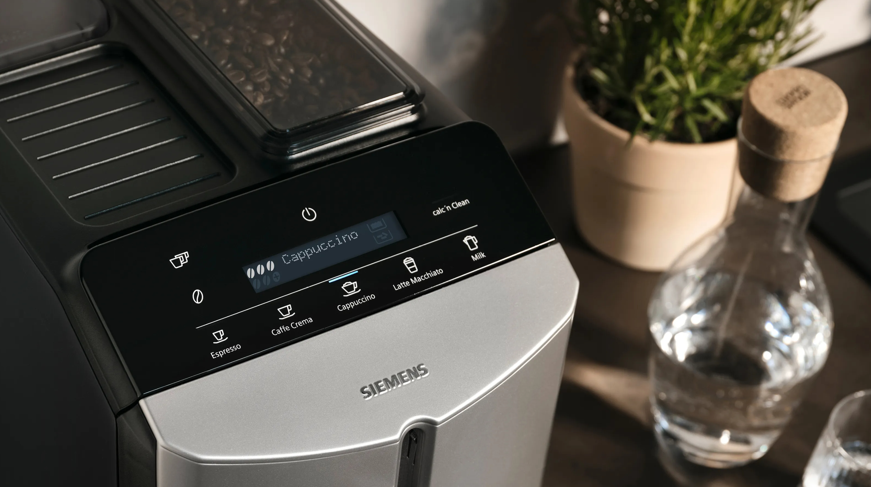 Ekspres do kawy z ekranem, przyciskami i karafką na wodę. Czarny i srebrny.