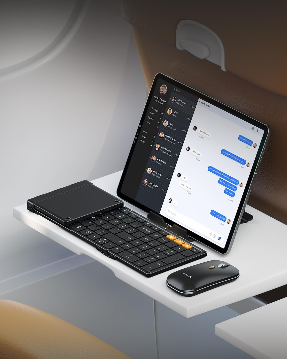 A tablet with a keyboard and mouse on a tray, in a plane setting.