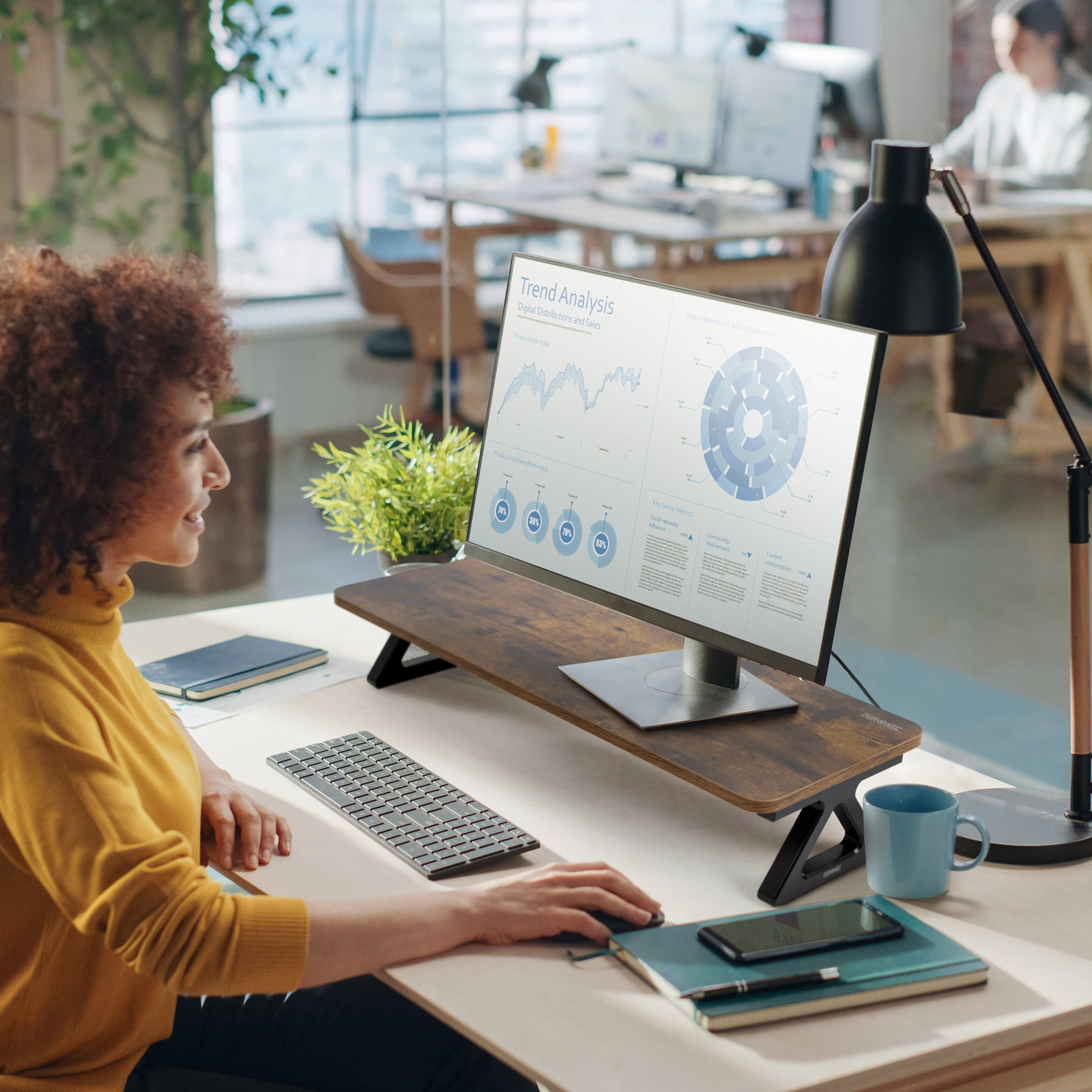 Frau benutzt Computer mit Monitorständer, Schreibtisch-Setup.