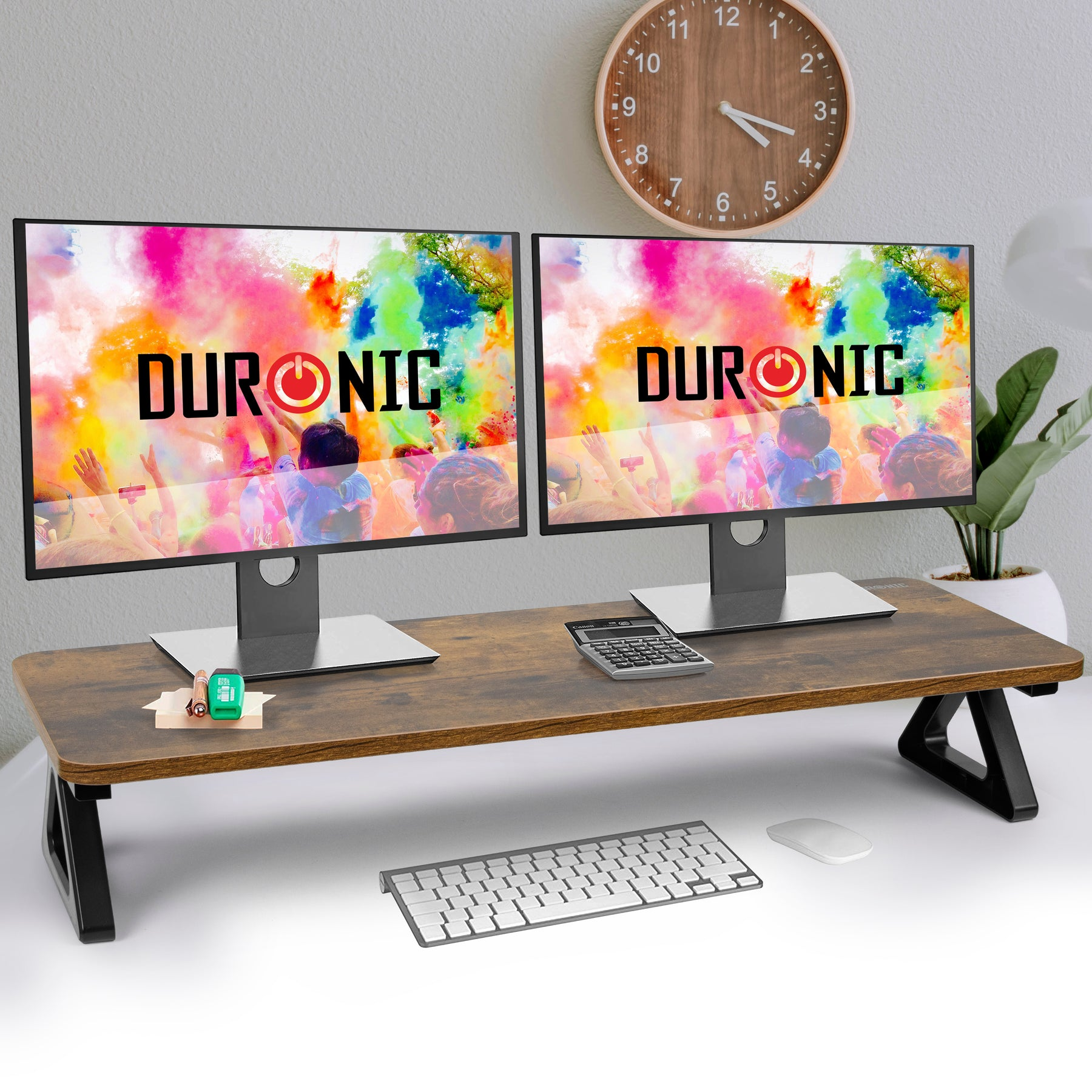 Zwei Monitore auf einem Schreibtisch zeigen das Wort DURONIC. Tastatur, Maus und Uhr sind vorhanden.