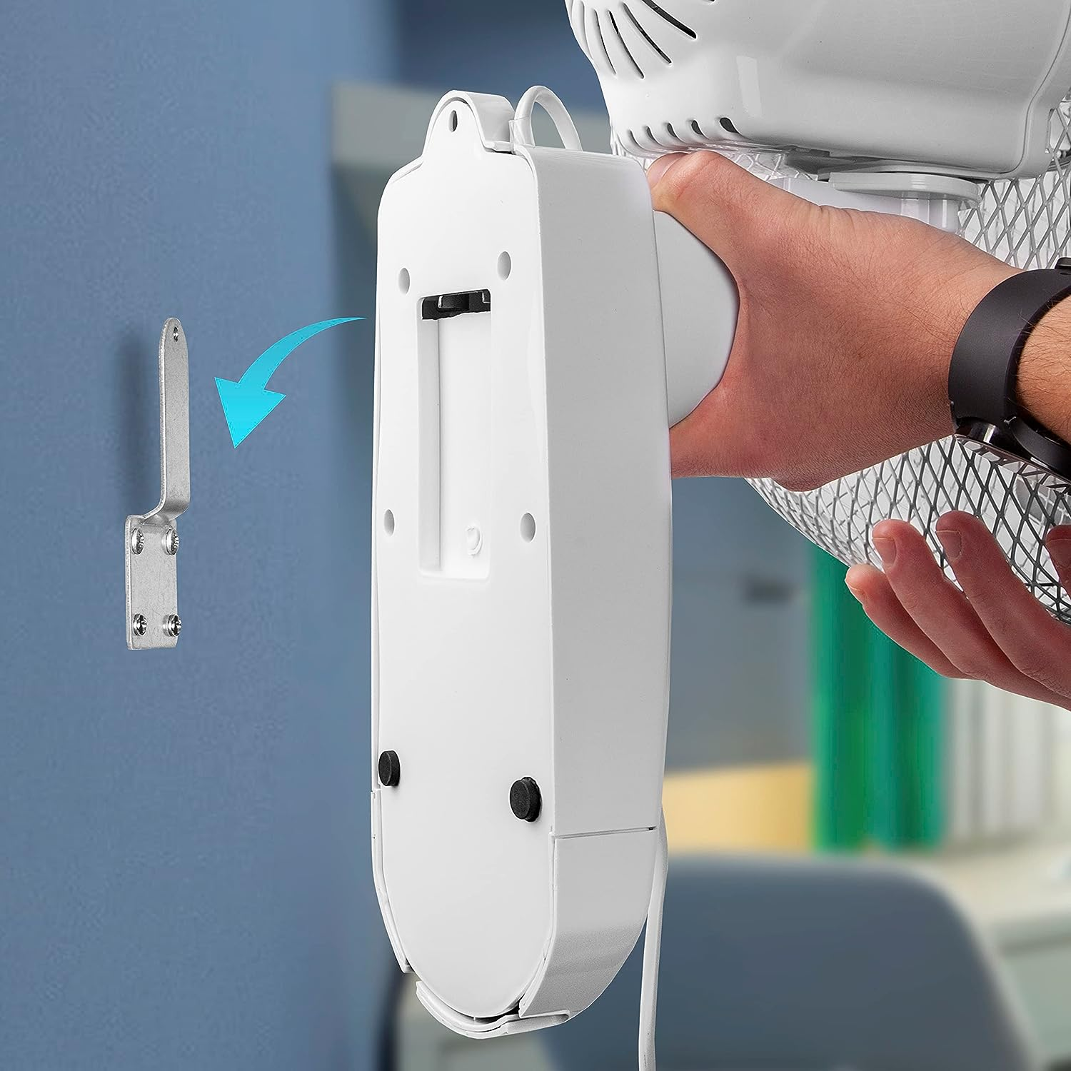 Weißer Ventilator mit Montagehalterung und Hand, die den Ventilator hält. Blauer Wandhintergrund.