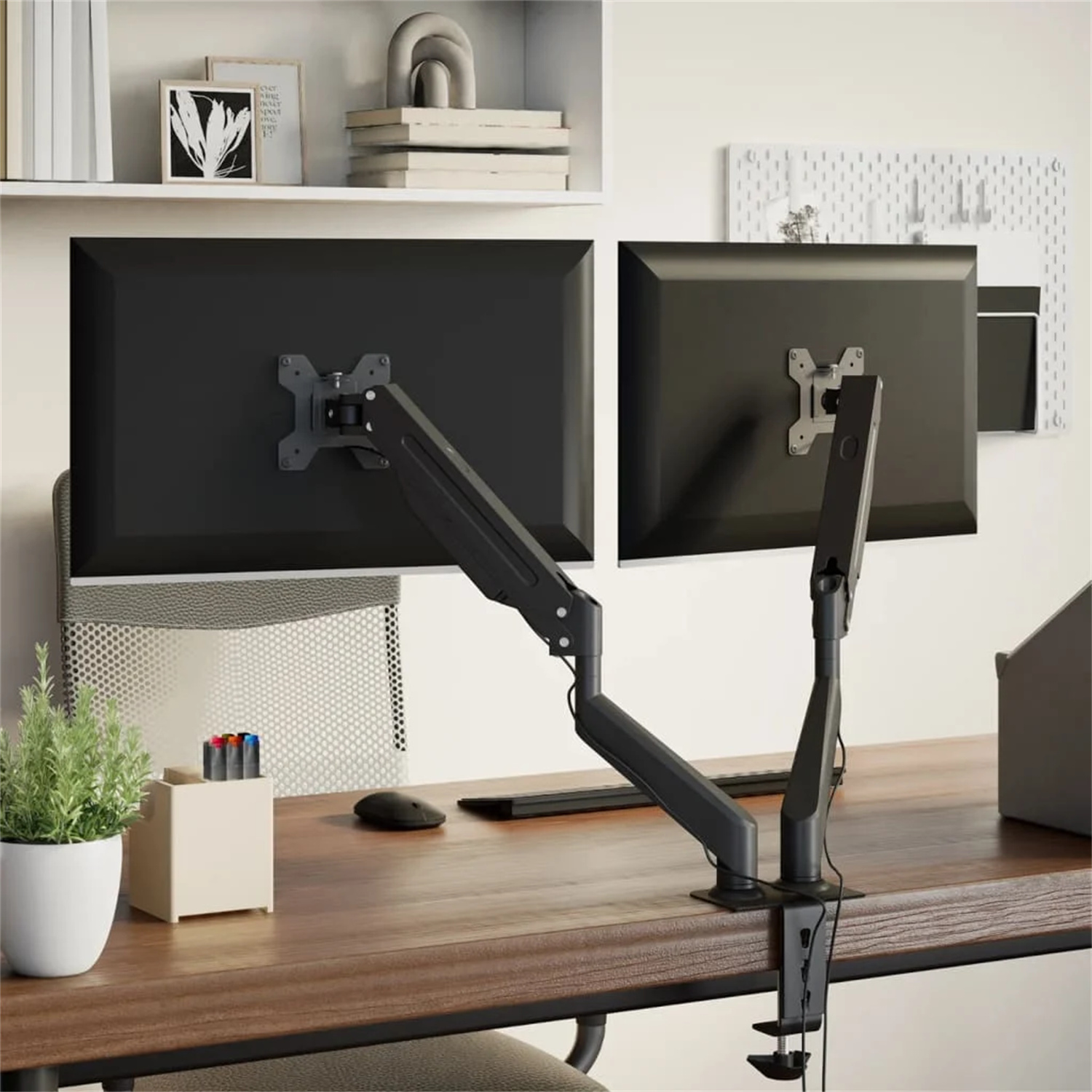 Doppel-Monitor-Setup mit schwarzen Monitoren und Armen auf einem Holzschreibtisch, mit Pflanze.