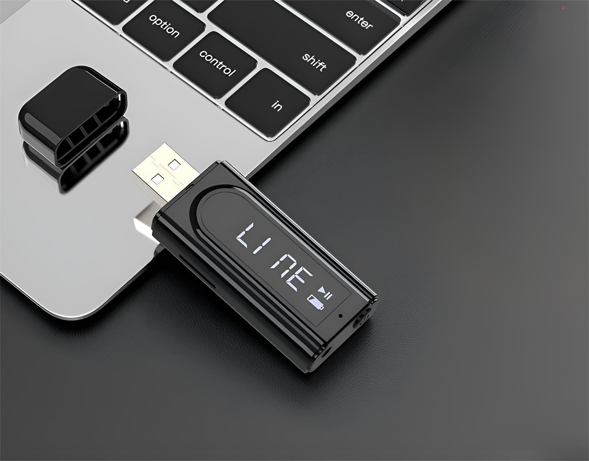 Schwarzer USB-Recorder auf einer Laptop-Tastatur, neben seinem schwarzen Deckel.