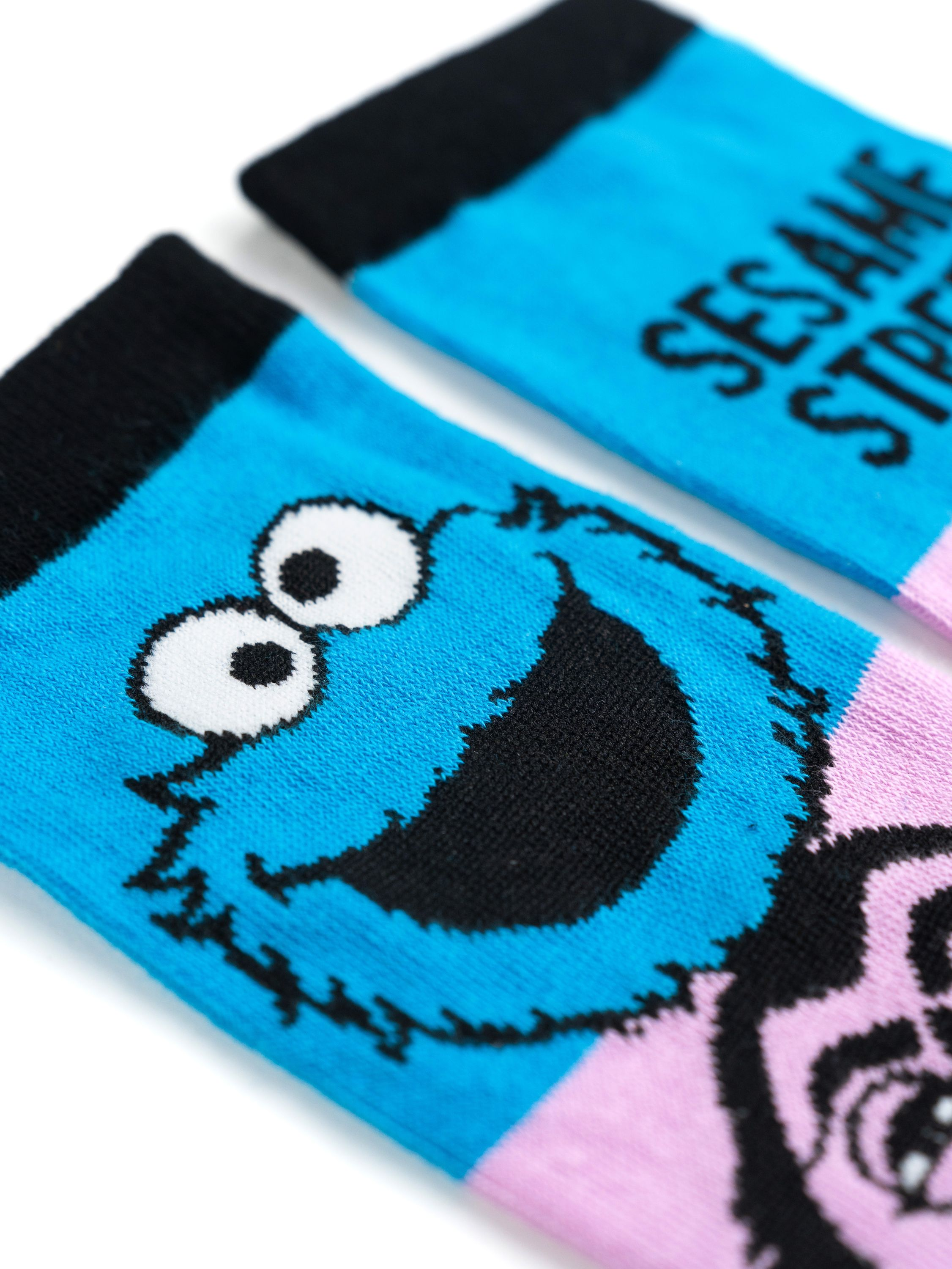 Nahaufnahme von zwei blauen Socken mit Krümelmonster darauf und den Worten 'SESAMSTRASSE'.