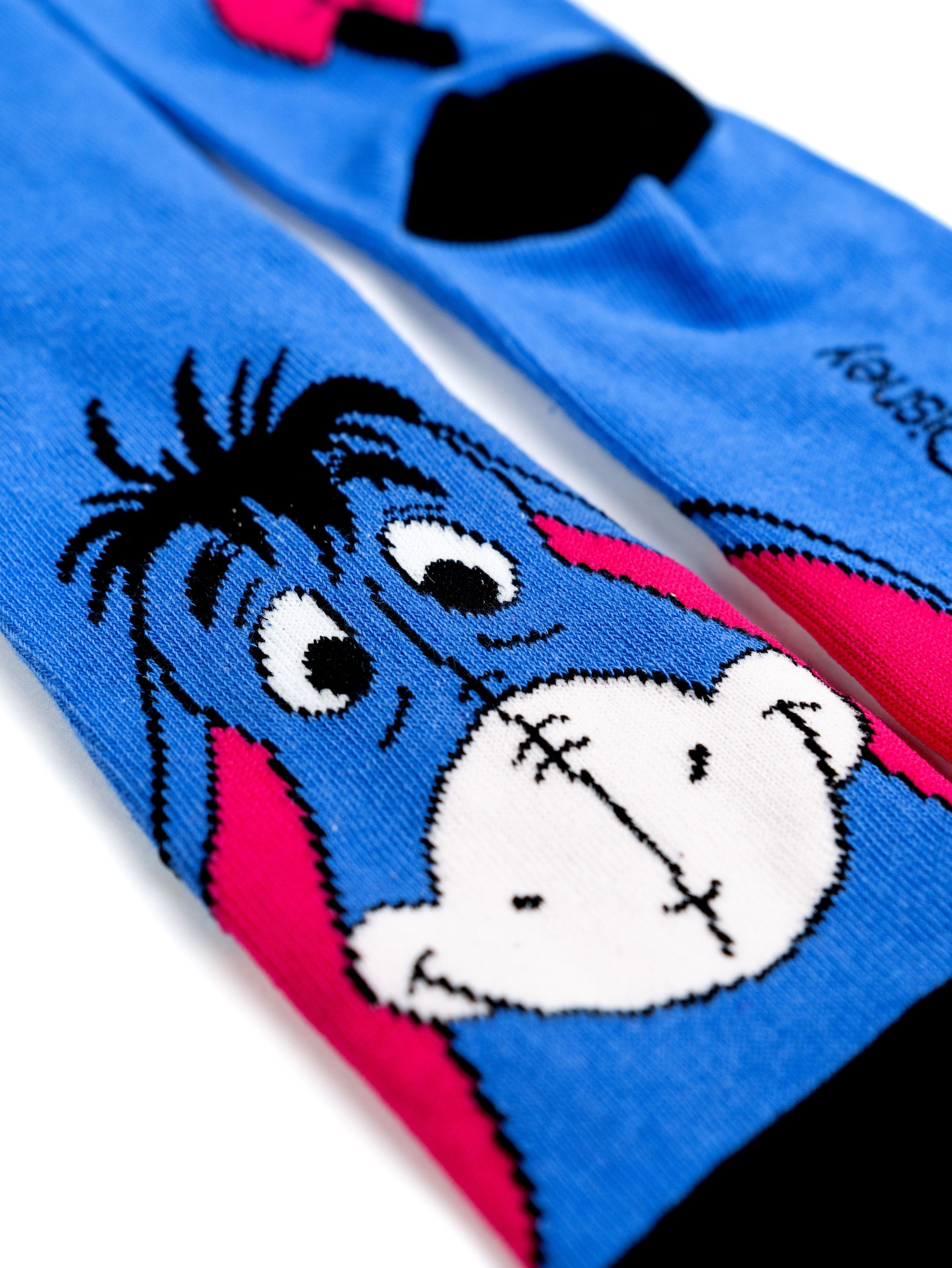 Blaue Socken mit Eeyore-Gesicht und rosa Akzenten.