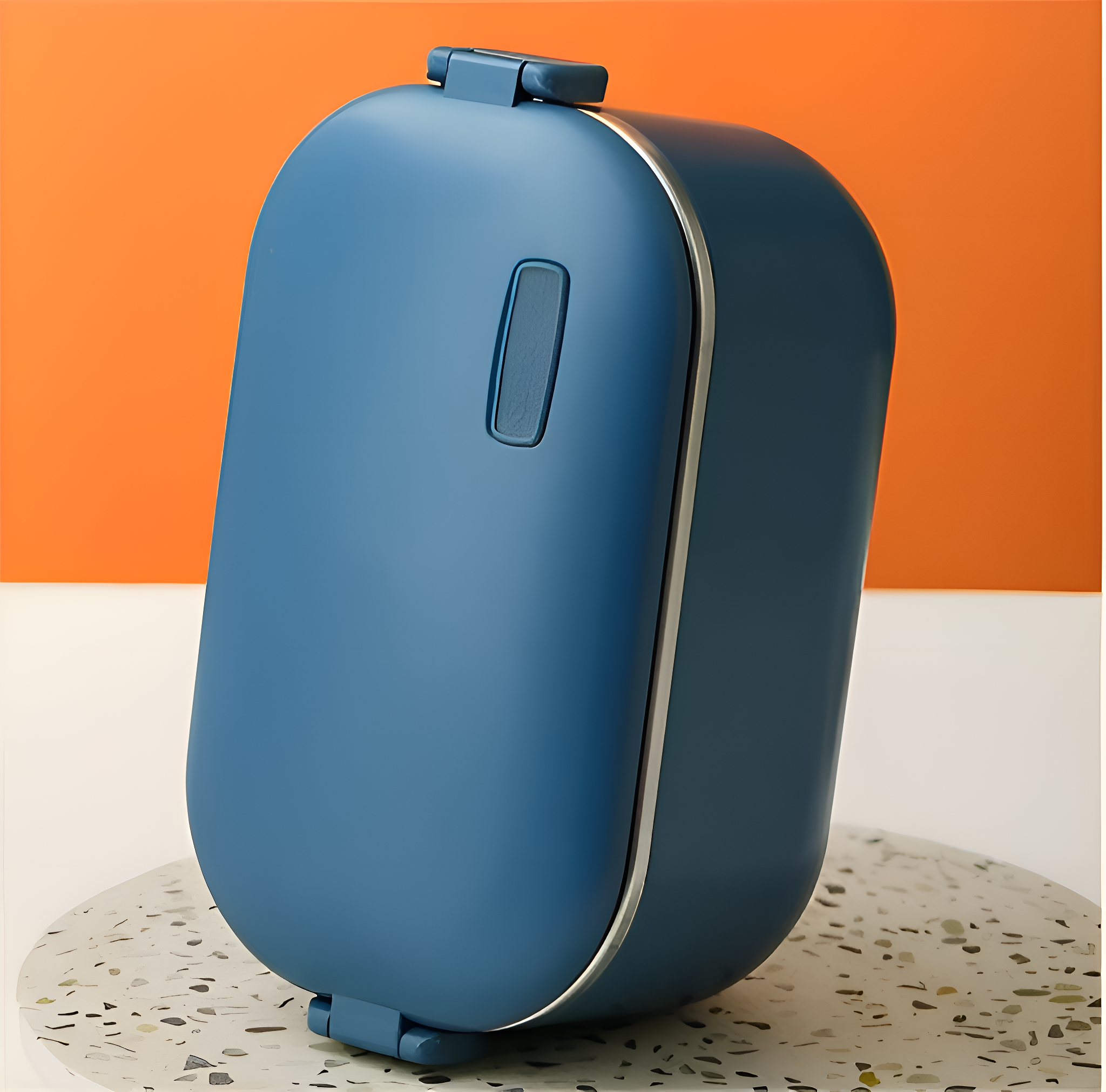 Eine blaue Brotdose steht auf einer gemusterten Oberfläche, mit orangefarbenem Hintergrund.