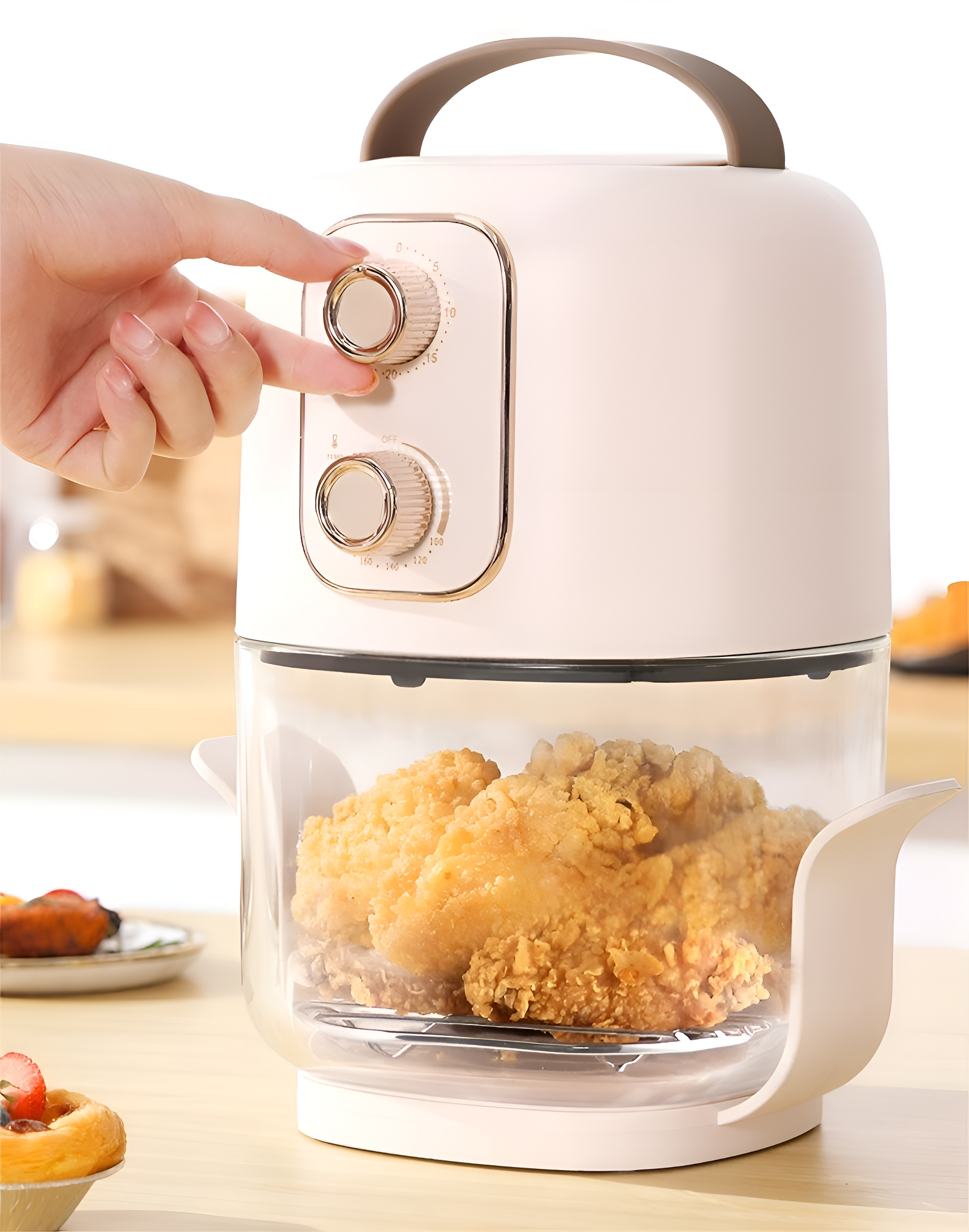 Ein weißer, cremefarbener Luftfritteuse mit Griff. Hand dreht einen Knopf. Frittiertes Hühnchen im Glasbehälter.