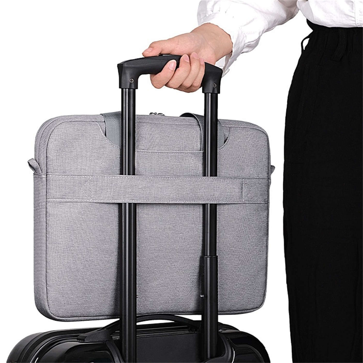 Eine Person hält eine graue Laptoptasche, die an einem Rollkoffergriff befestigt ist. Die Hülle ist grau.