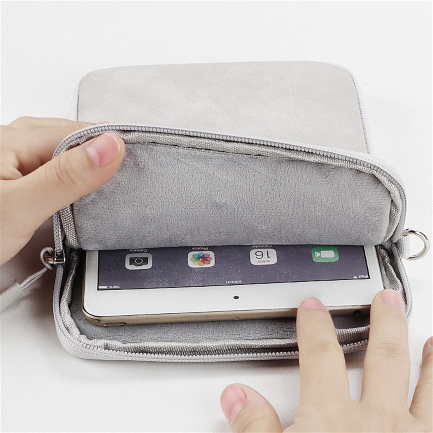 Hände, die ein Tablet in einer grauen Tasche mit Reißverschluss halten.
