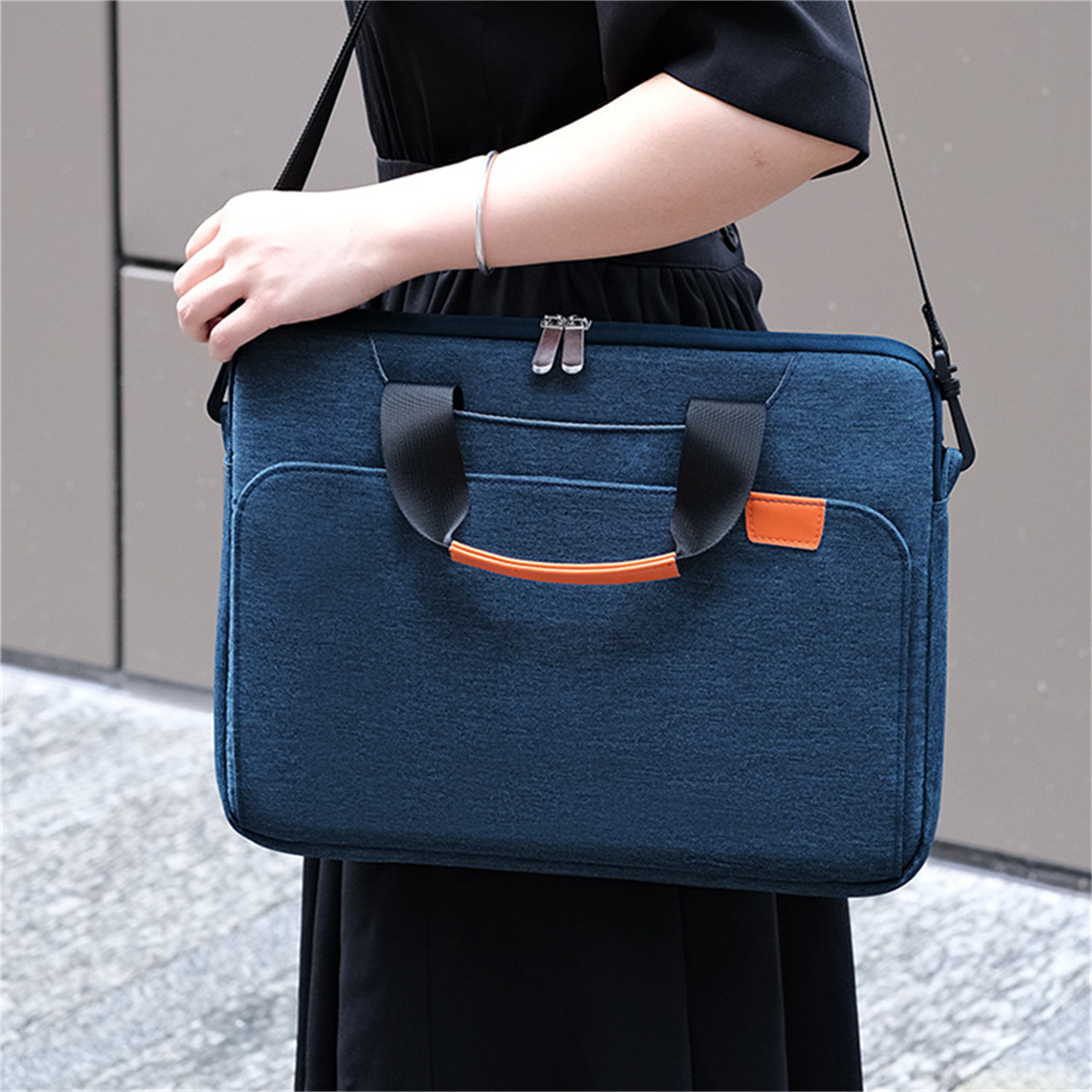 Eine Person, die eine blaue Tasche mit Henkel und Schulterriemen hält.