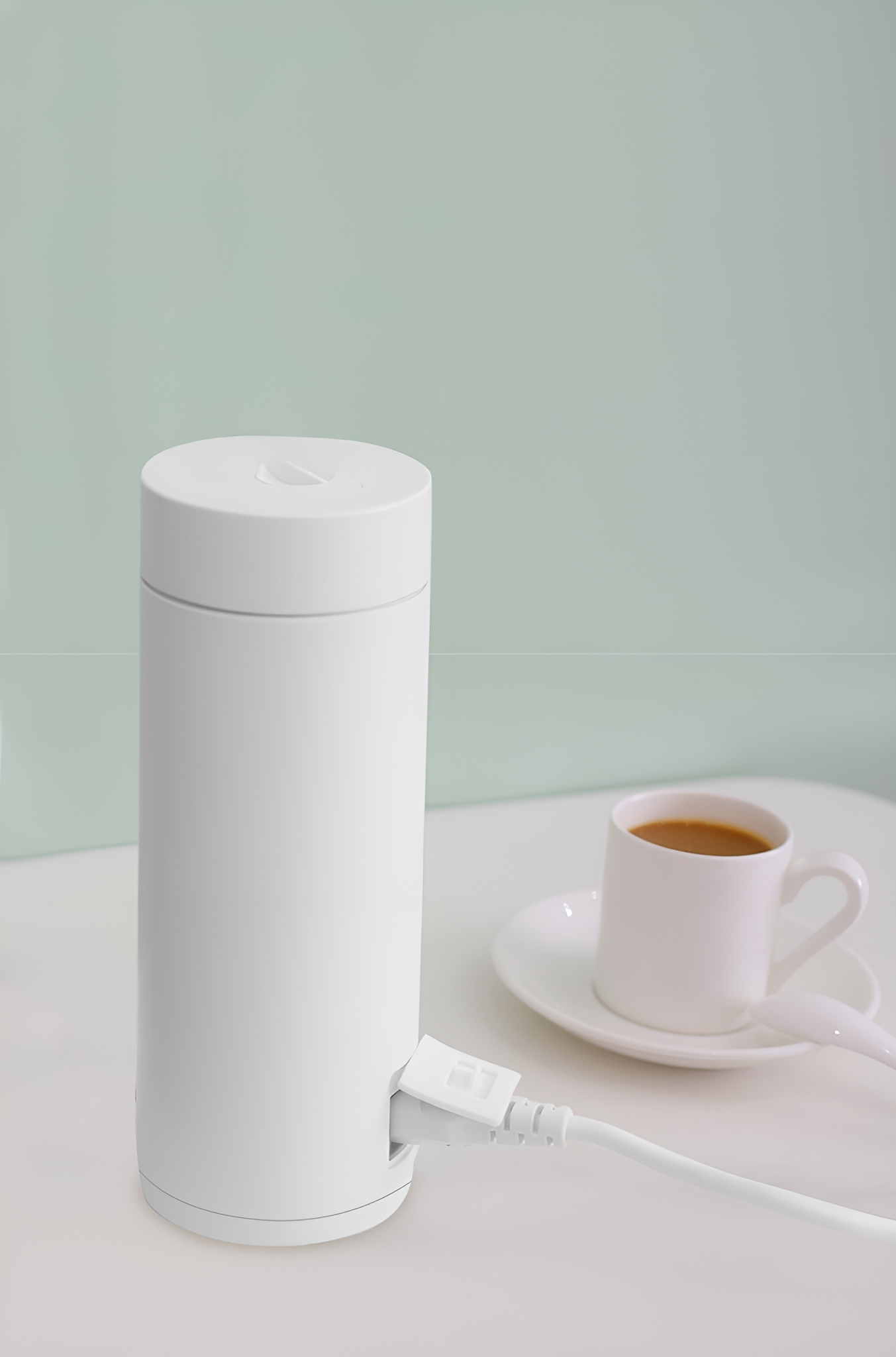 Ein weißer elektrischer Wasserkocher mit Kaffeetasse, weißem Kabel und Stecker.