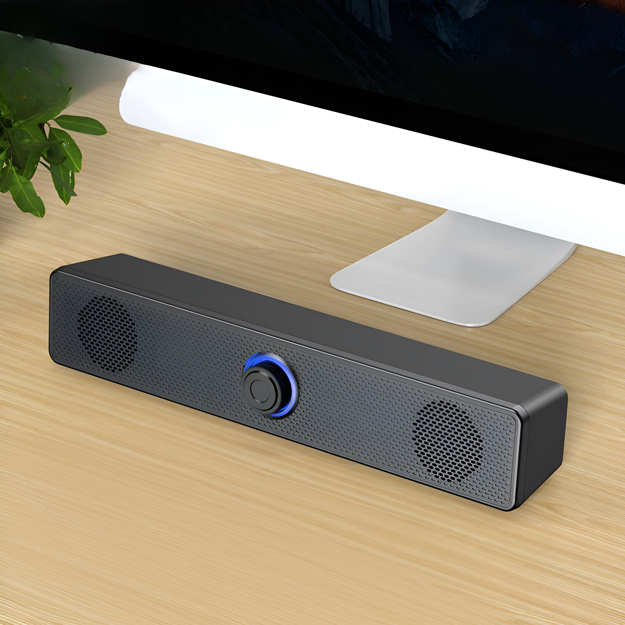 Schwarze Soundbar mit blauem Licht auf einem Holzschreibtisch vor einem Computer.
