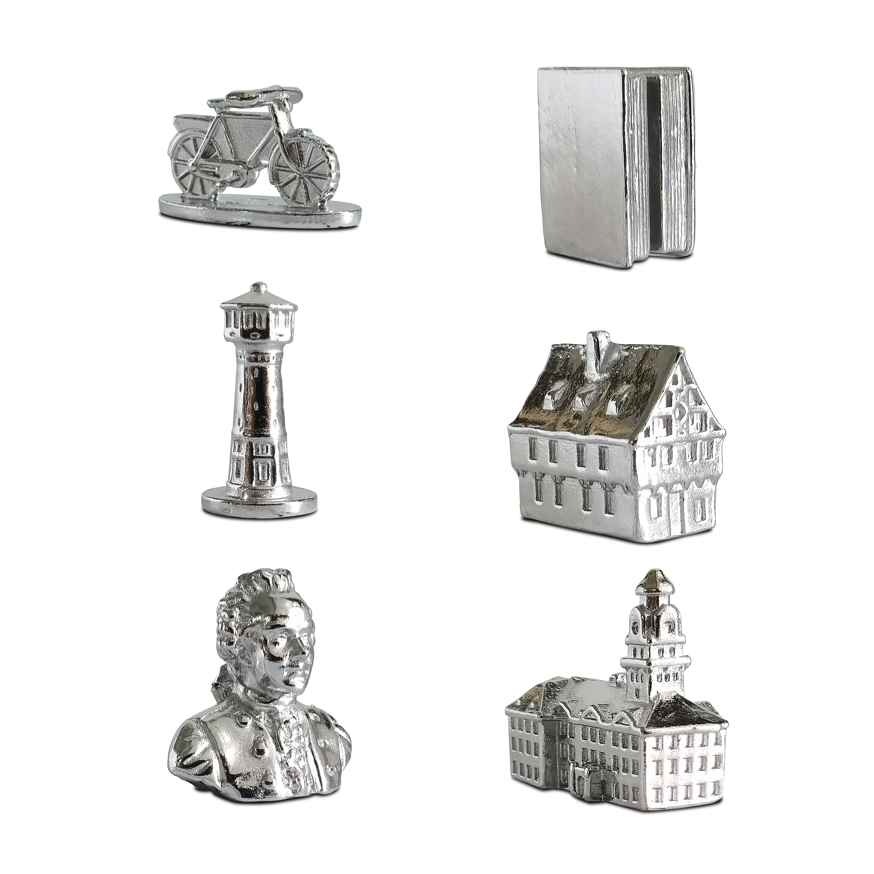 Silberne Metallfiguren: Fahrrad, Bücher, Leuchtturm, Haus, Büste und Gebäude auf weißem Grund.