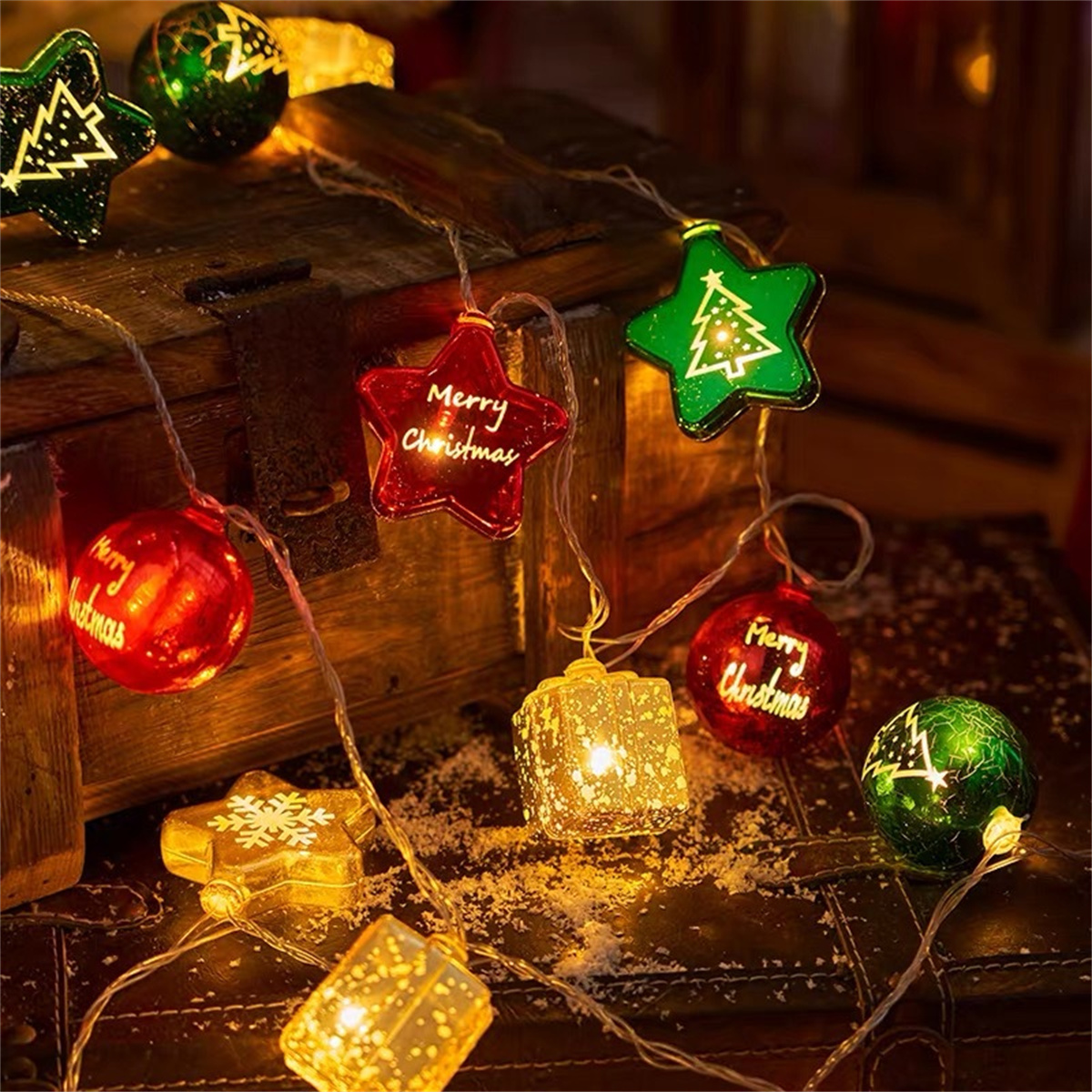 Weihnachtsbeleuchtung mit Stern- und runden Ornamenten. Sie sind rot, grün und gold. Die Lichter sind an.