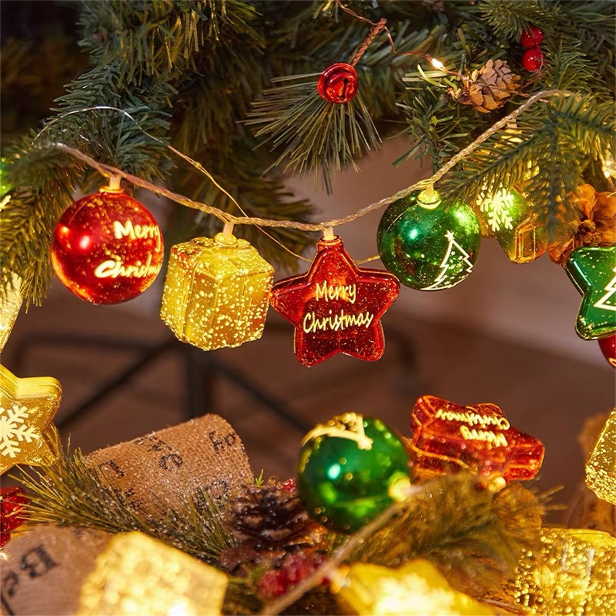 Weihnachtsbaumschmuck in Rot, Grün und Gold mit Text „Frohe Weihnachten“ und Lichtern.