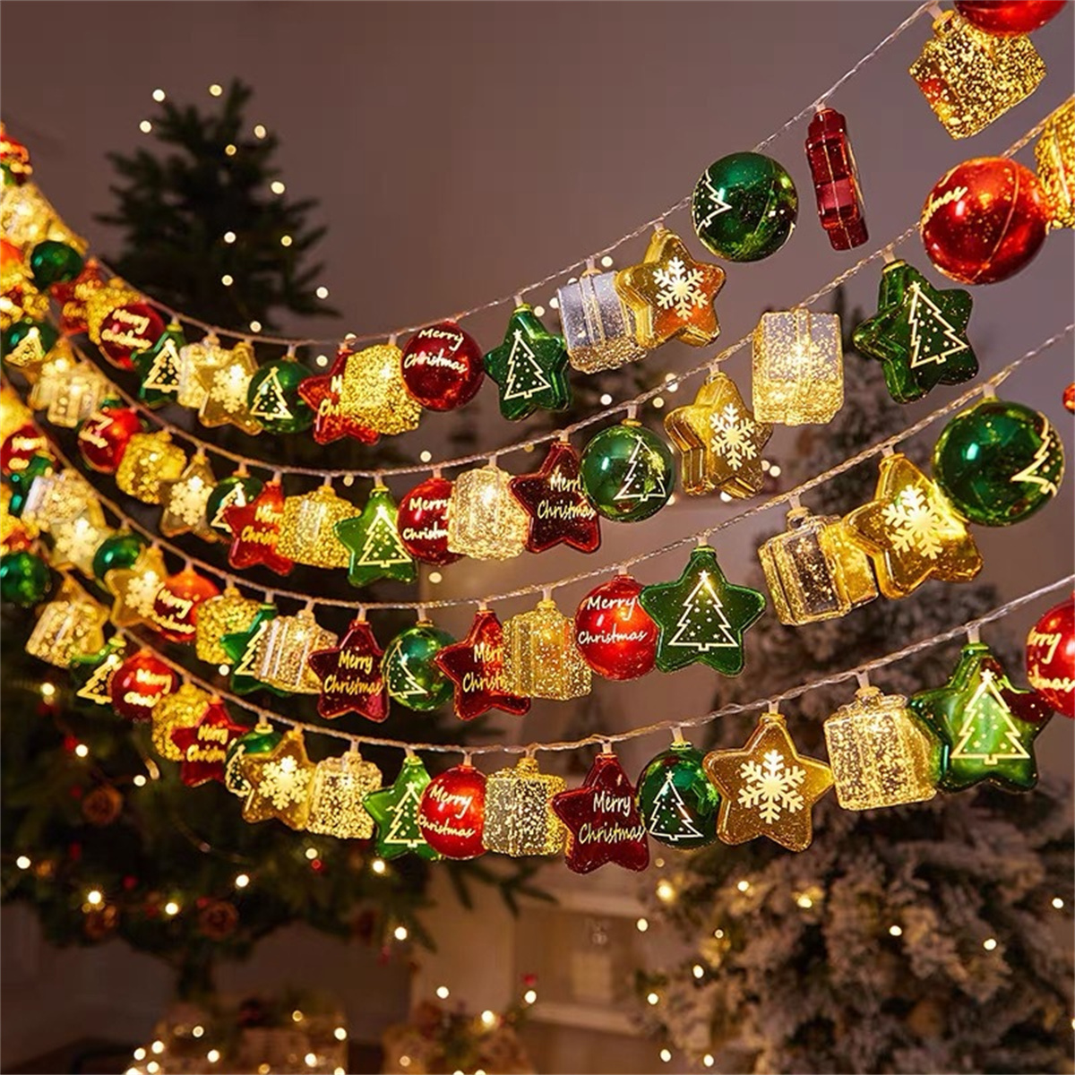 Weihnachtsbeleuchtungsgirlande mit Ornamenten. Rote, grüne und goldene Ornamente mit „Frohe Weihnachten“.