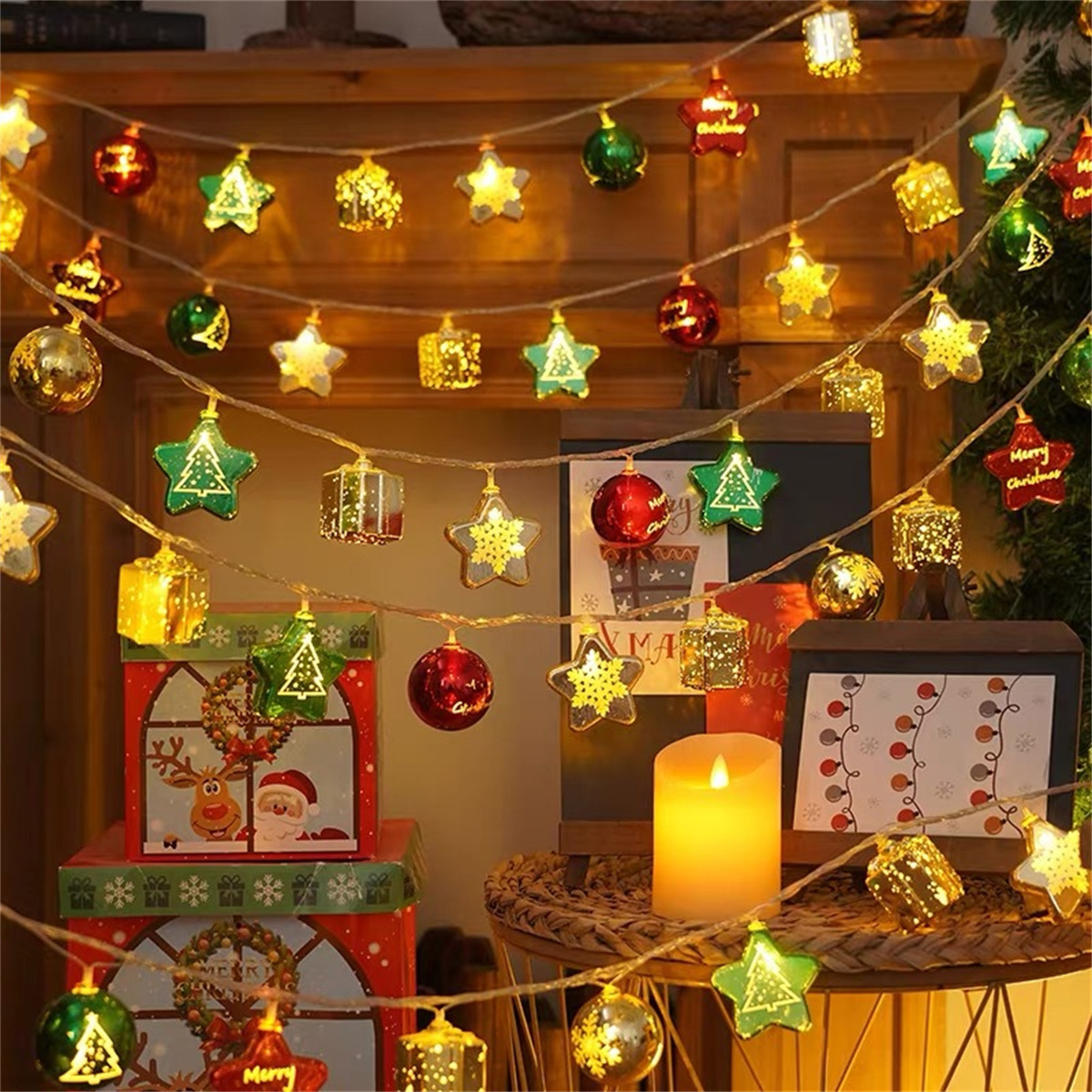 Weihnachtsbeleuchtung, Ornamente und eine brennende Kerze auf einem Tisch.