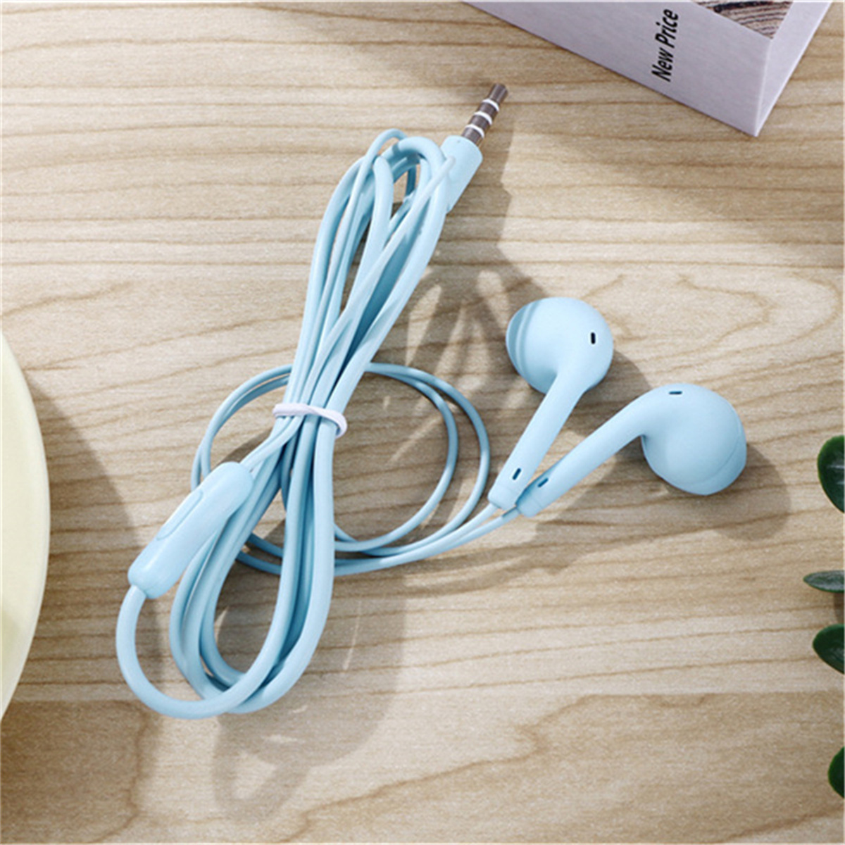 Hellblaue Ohrhörer und Kabel auf Holzoberfläche. Weißes Etikett im Hintergrund sichtbar.