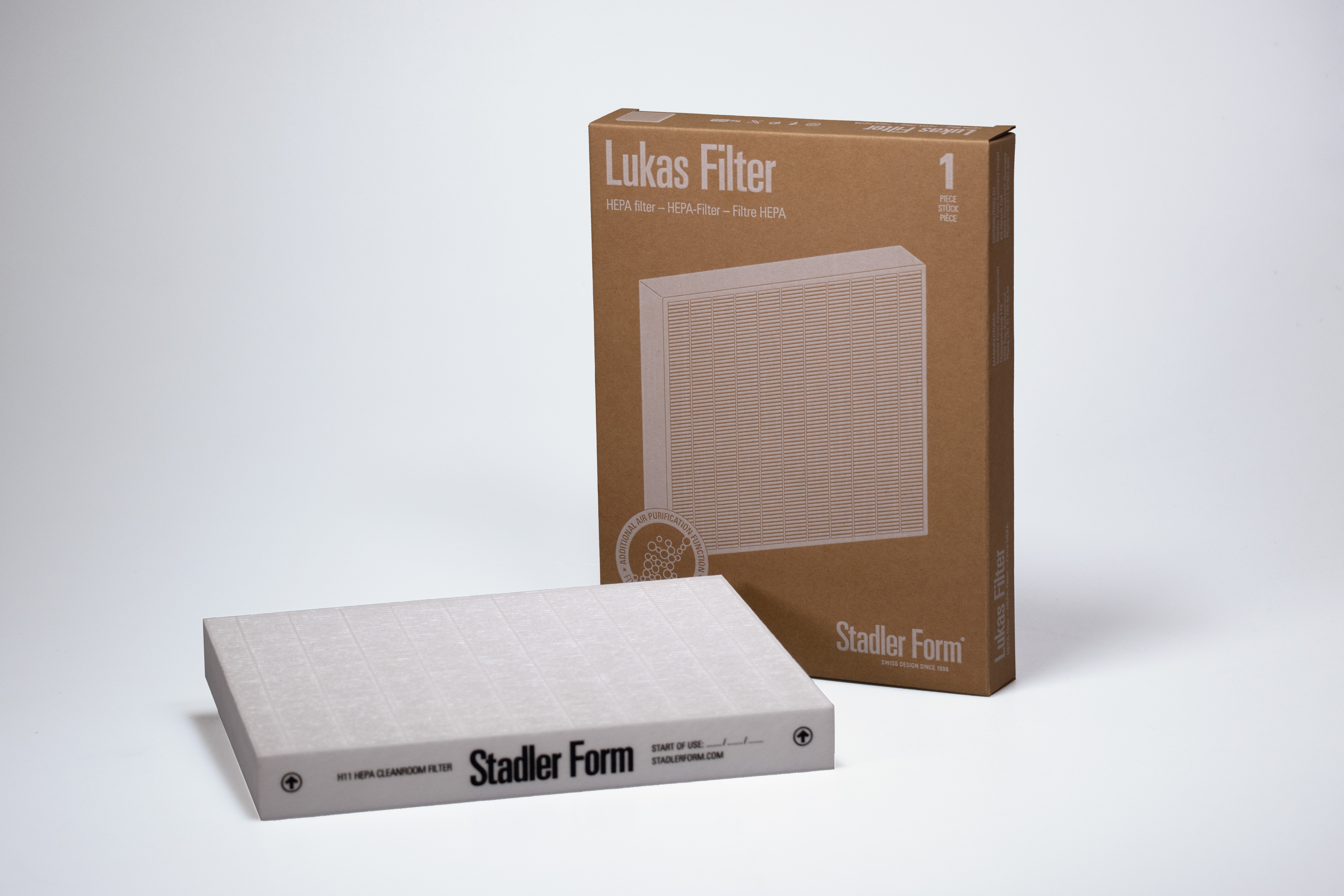 Two air filters with a box. The filters are white and have a grid pattern. The box is brown with text.