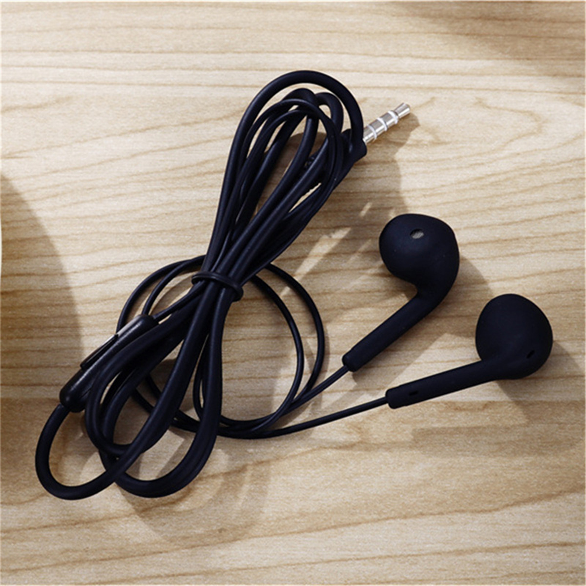 Schwarze Kopfhörer mit schwarzem Kabel auf Holzoberfläche.