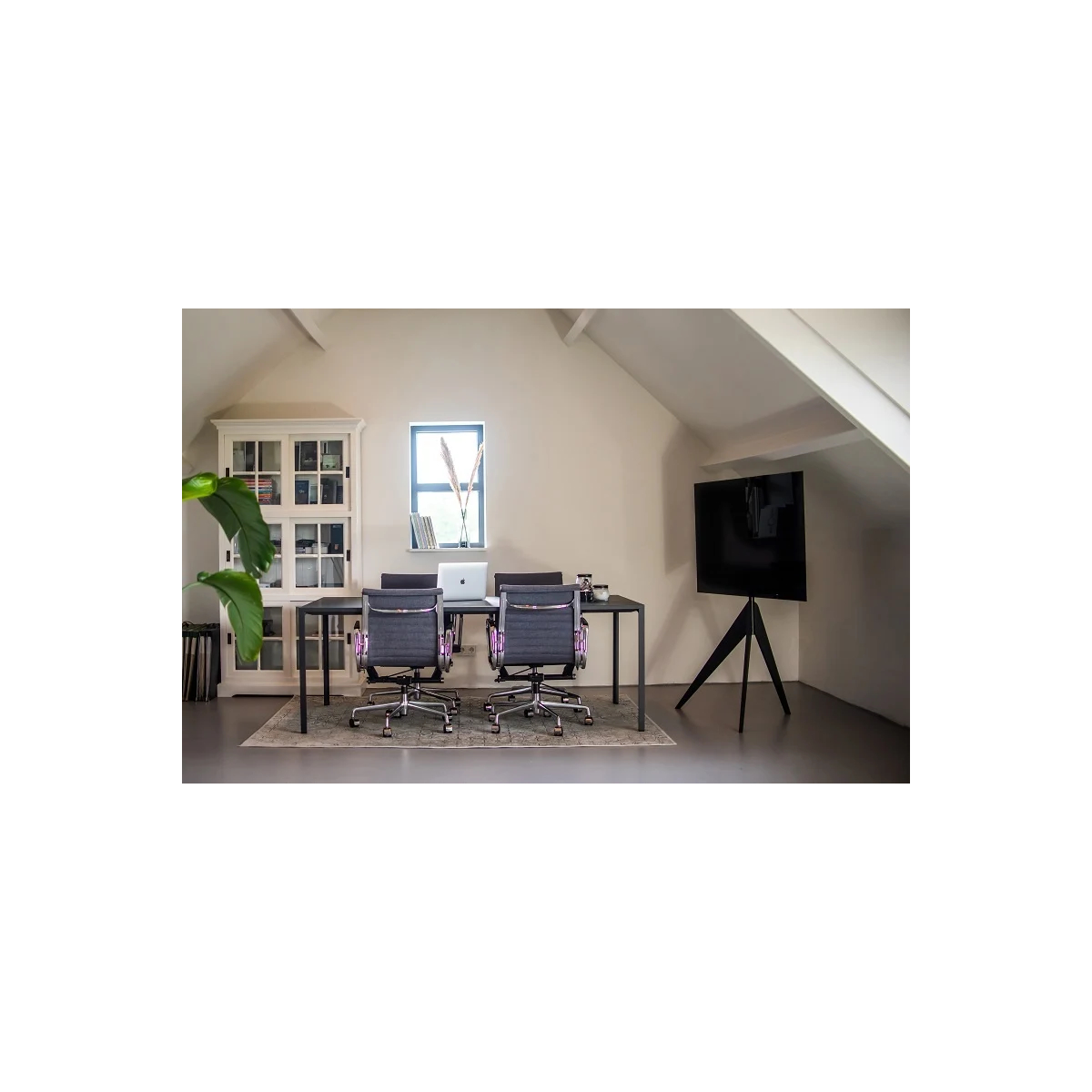 Modern kantoorinterieur. Twee zwarte bureaus met stoelen, een raam en een tv op een standaard.