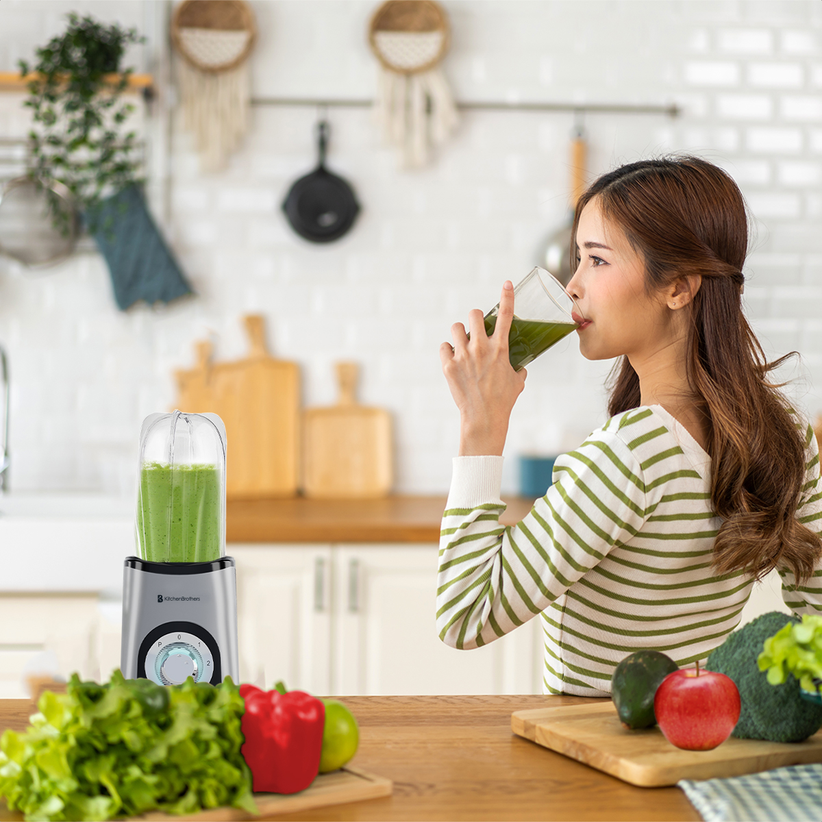 Woman drinking green smoothie from a blender next to fruits and vegetables.