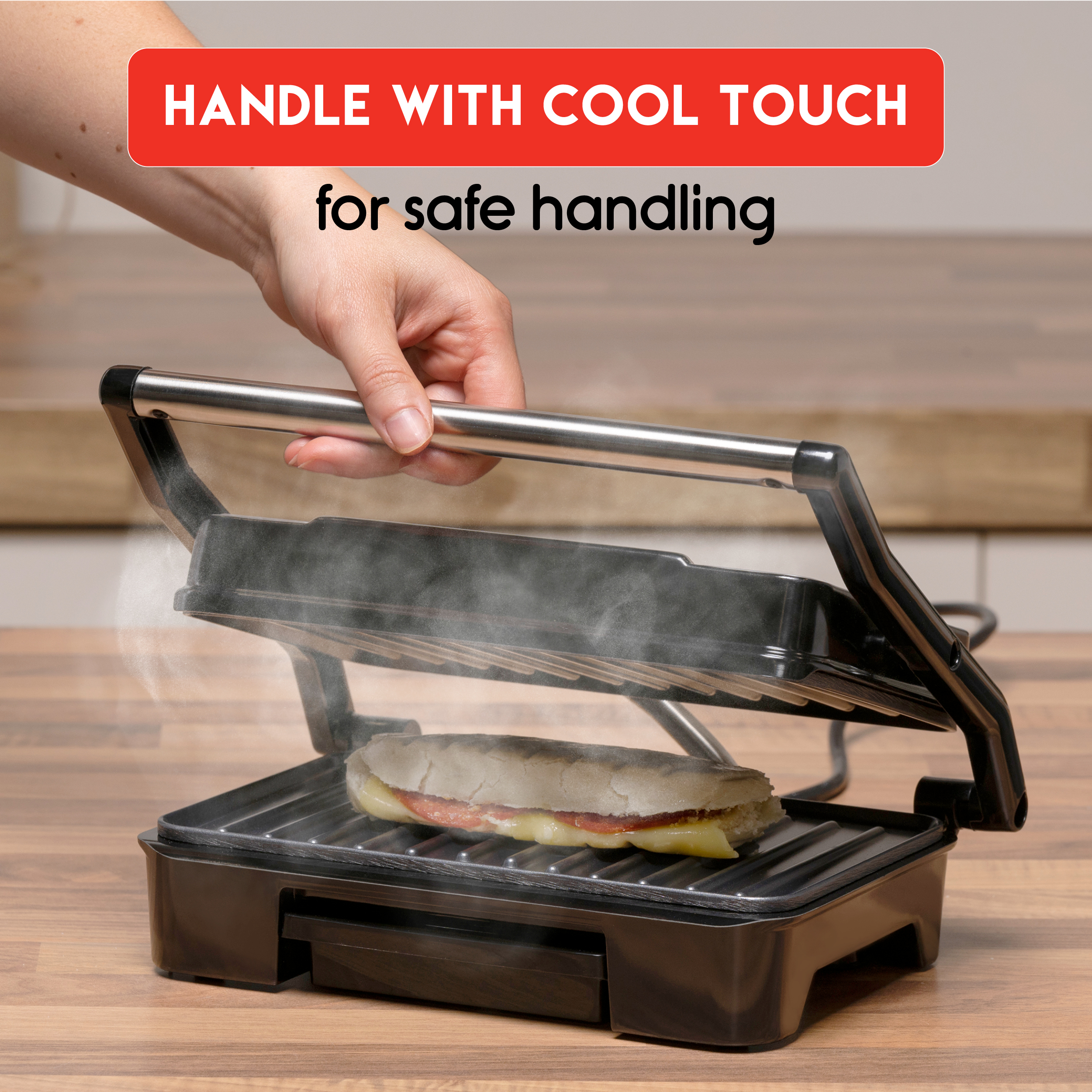 Black panini press with sandwich. Hand holding. Black background.