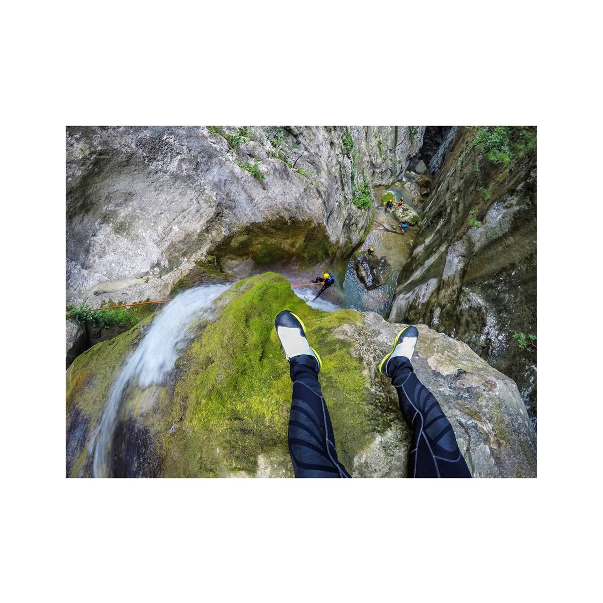 Widok z pierwszej osoby na kanion z turystą poniżej i ścianami skalnymi otaczającymi wodospad.