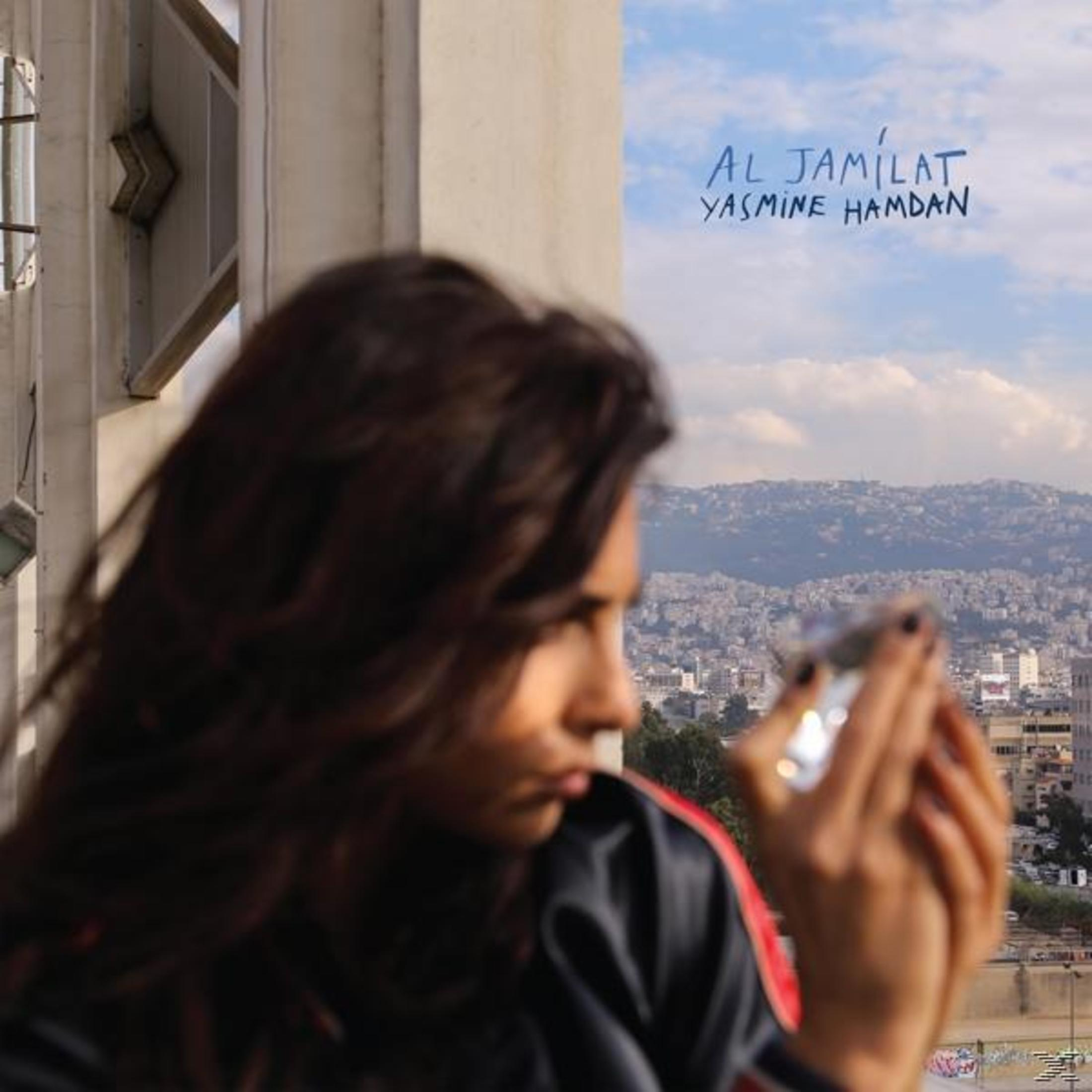 Femme tenant un miroir avec vue sur la ville et ciel en arrière-plan.