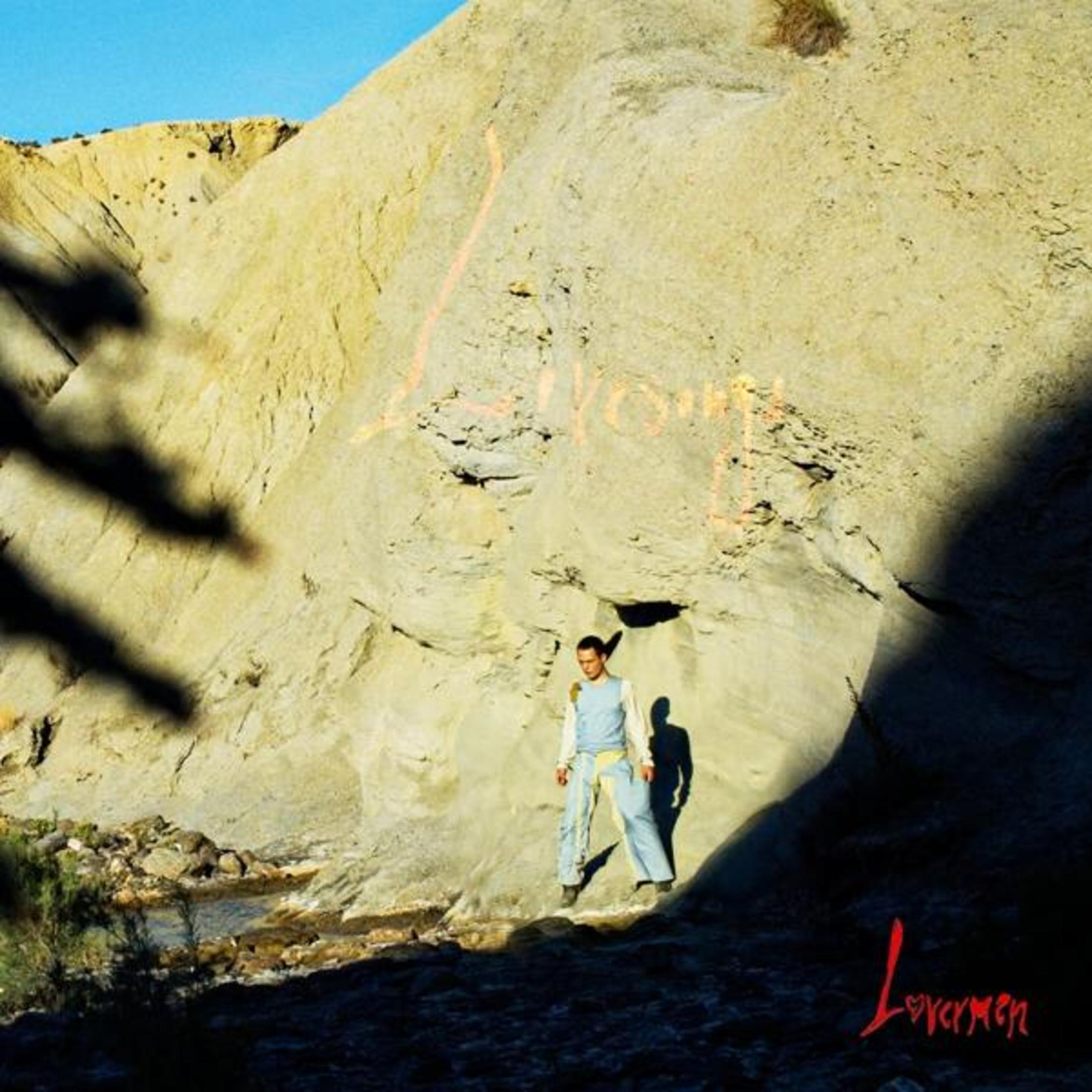 Un uomo davanti a una grande roccia chiara con la parola 'LOVE' in rosa.