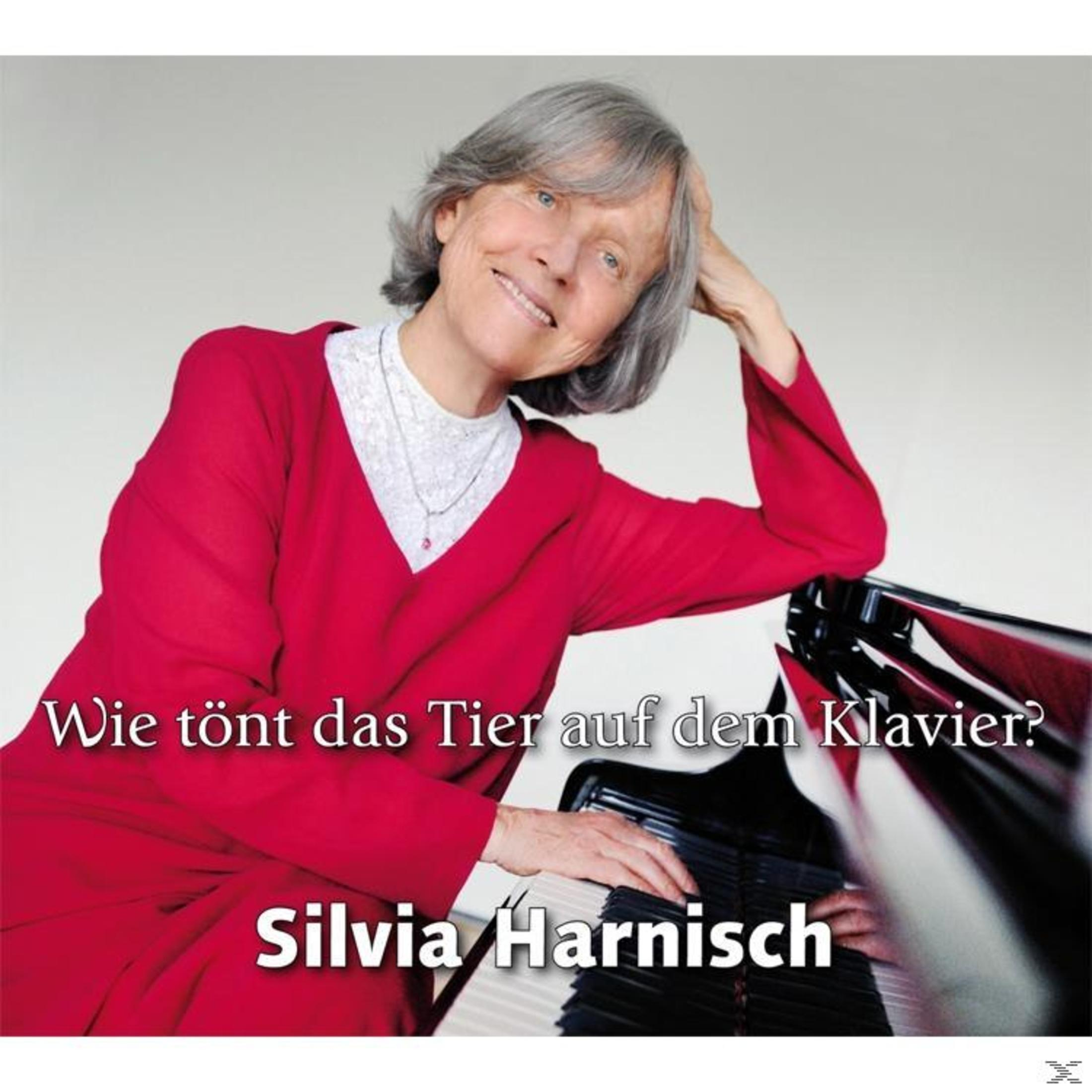 Femme en robe rouge souriant devant un piano. Texte en allemand : 'Comment sonne l'animal sur le piano ?'.