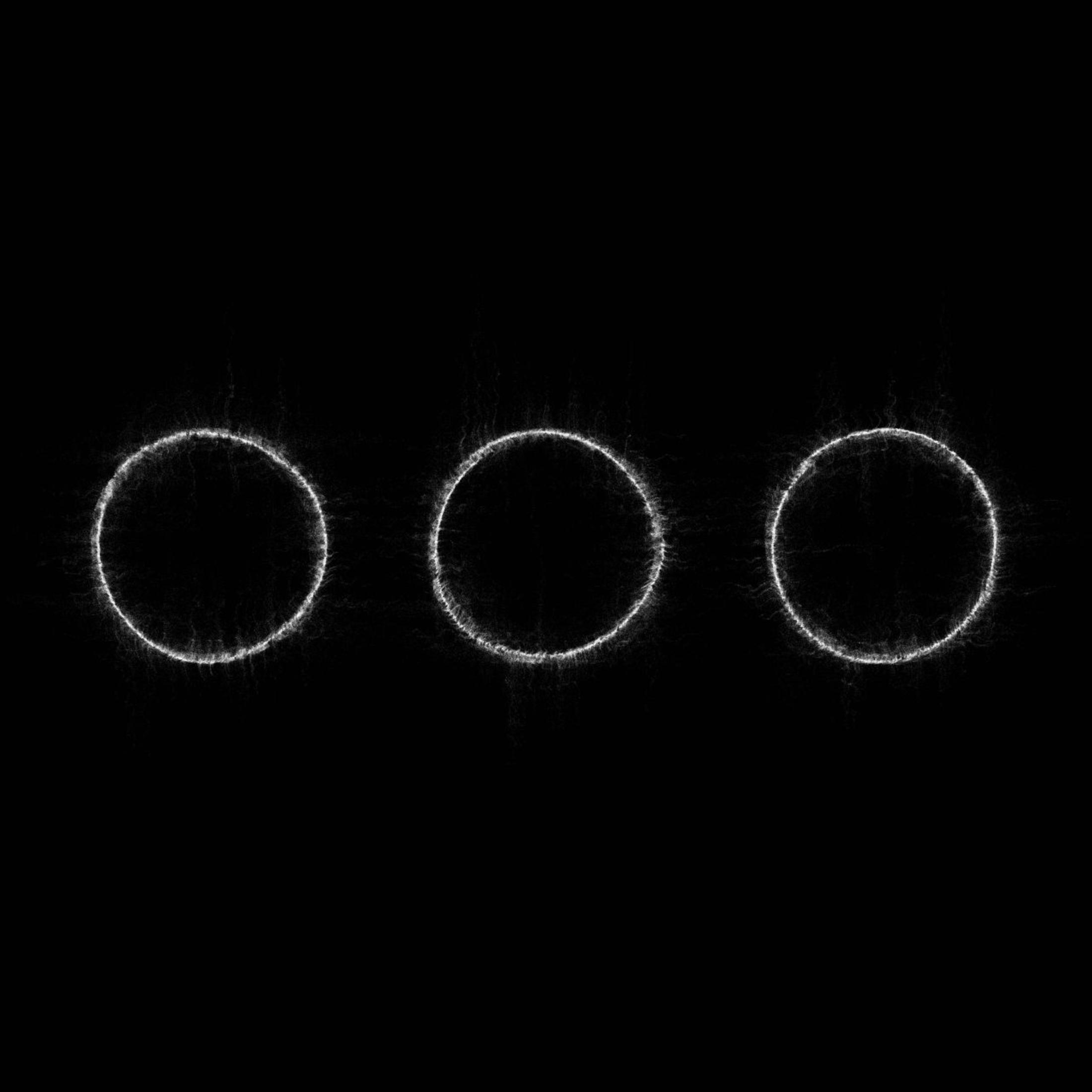 Drie gloeiende witte cirkels op een zwarte achtergrond.