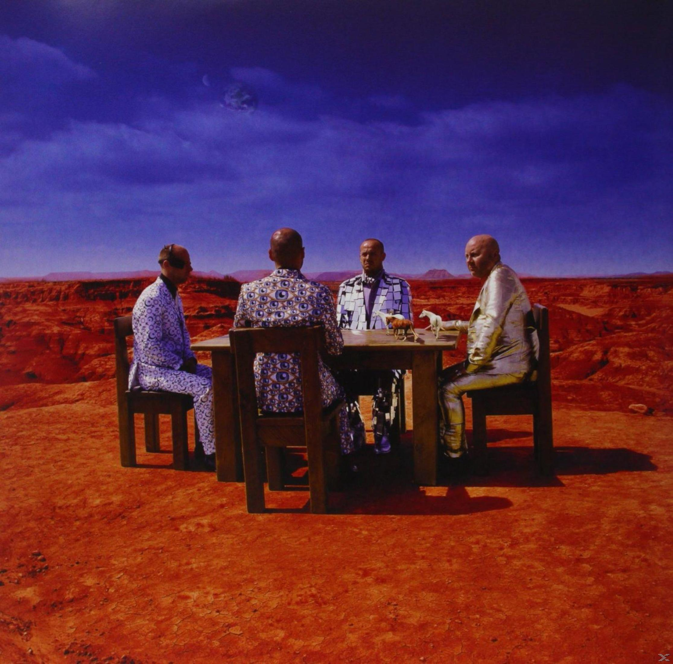 Quatre personnes en costumes autour d'une table sur une planète rouge. Ciel bleu avec une lune.