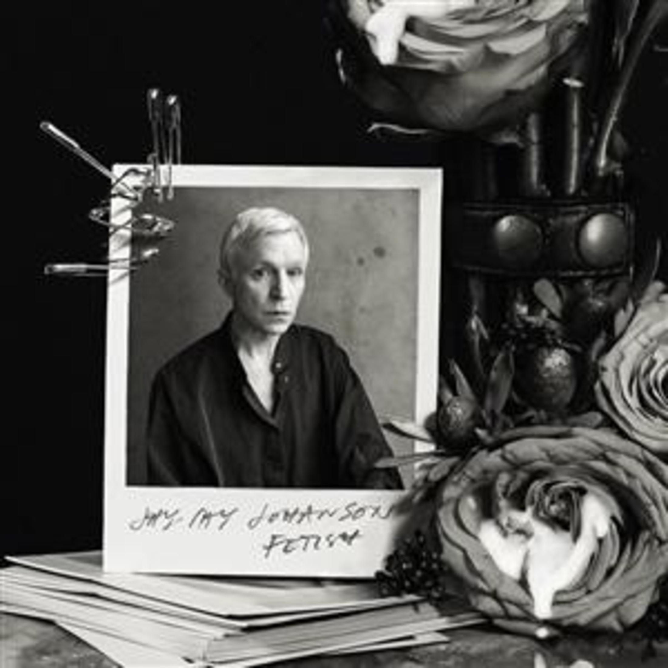 Foto in bianco e nero di una persona in ritratto. Fiori e una polaroid su un tavolo.