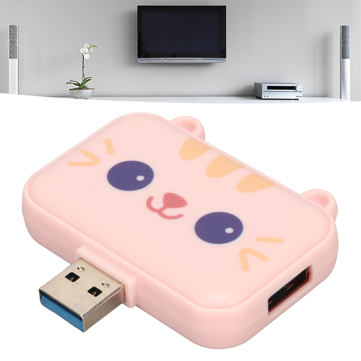 Ein rosa USB-Hub mit Katzen-Gesichts-Design. Der Hintergrund zeigt einen Fernseher, Lautsprecher und eine Pflanze.