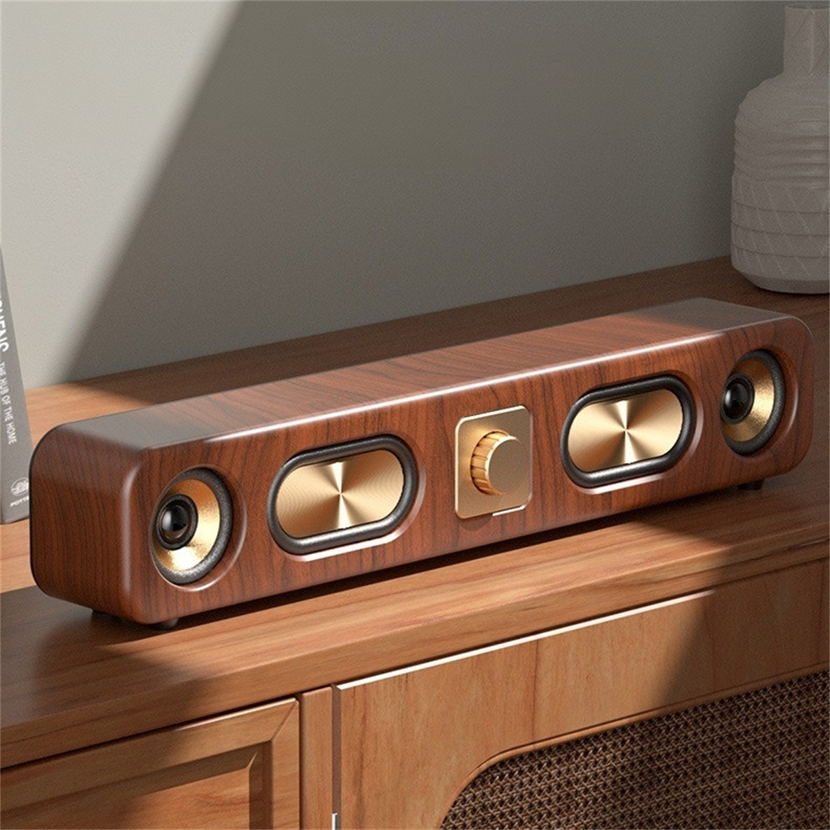Eine hölzerne Soundbar mit goldenen Lautsprechern und einem Lautstärkeregler. Sie steht auf einer Holzoberfläche.