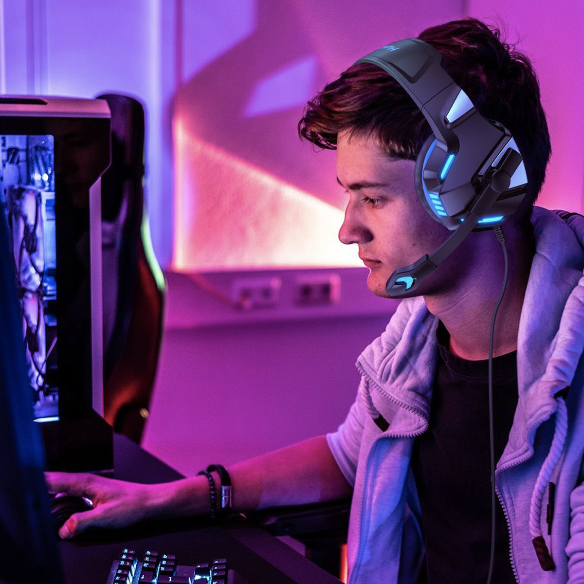 Ein Mann mit Headset zockt in einem dunklen Raum mit Neonlicht.