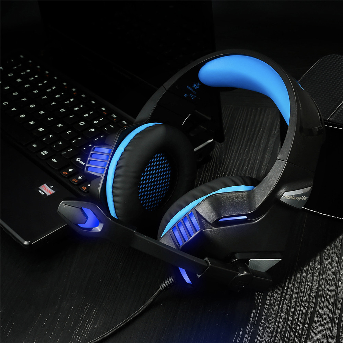 Schwarze und blaue Gaming-Kopfhörer auf einem Schreibtisch. Im Hintergrund ist eine Tastatur zu sehen.